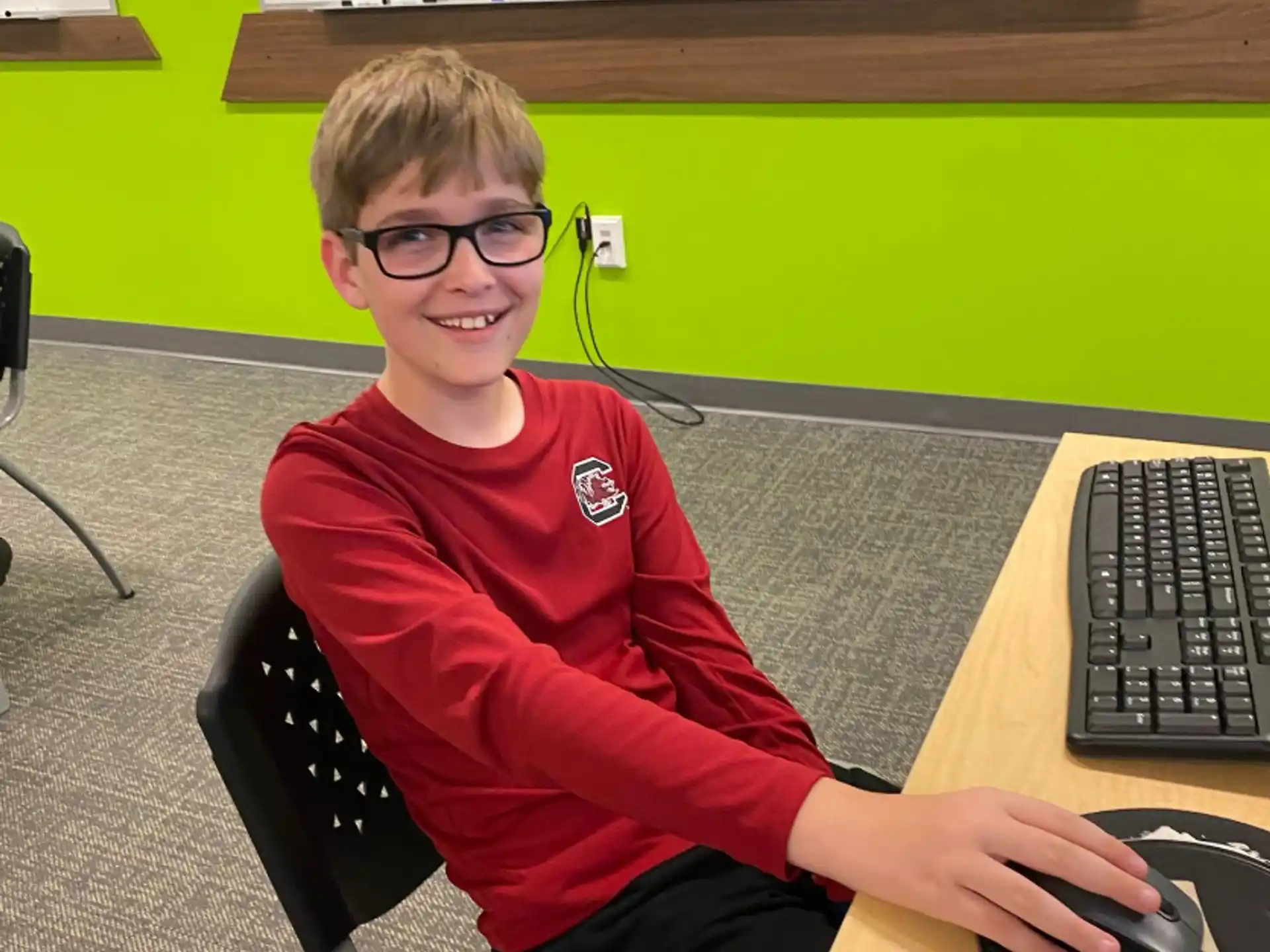 a boy sitting at a desk with a computer and mouse
