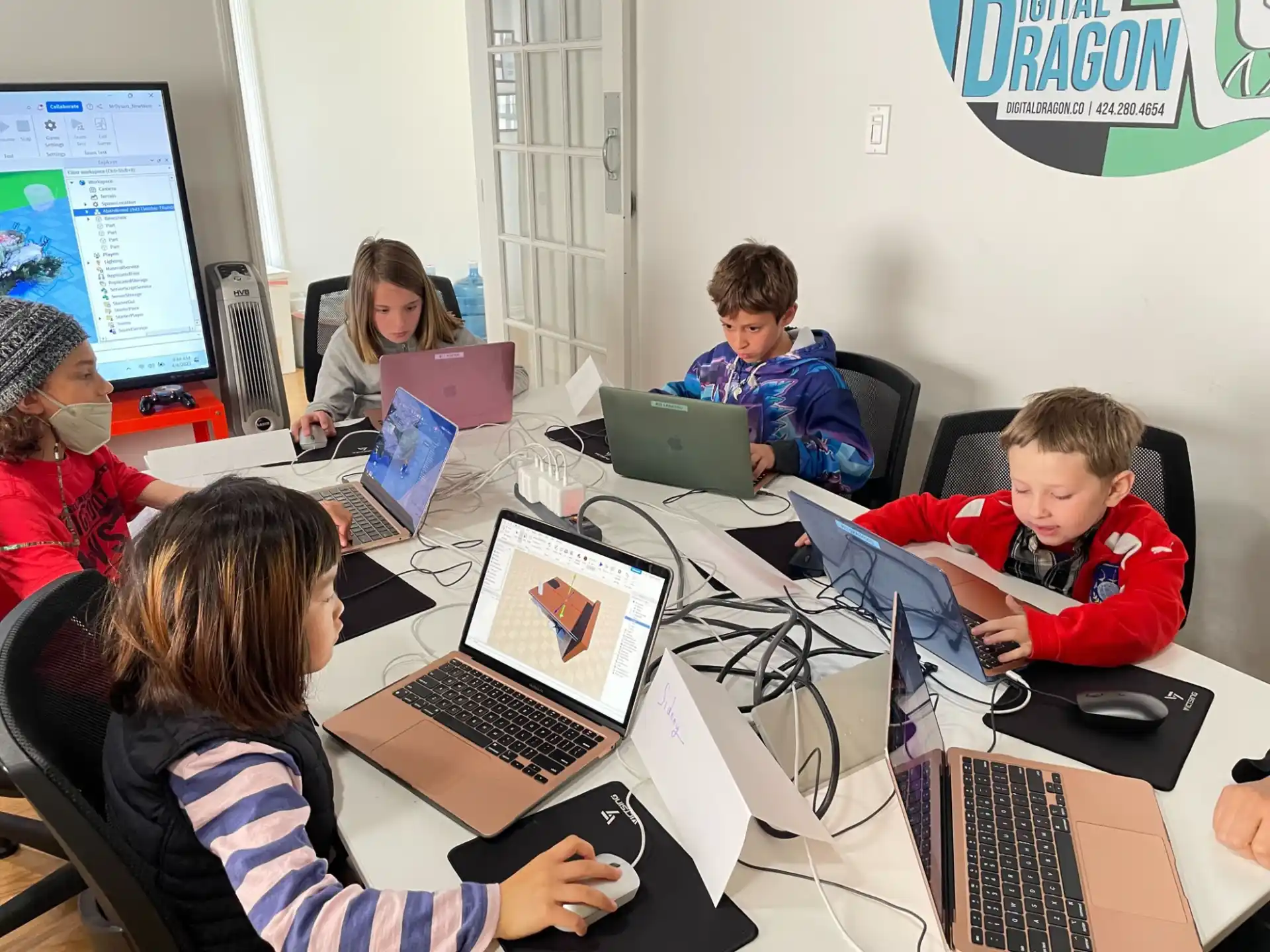 a group of people sitting at a table with laptops