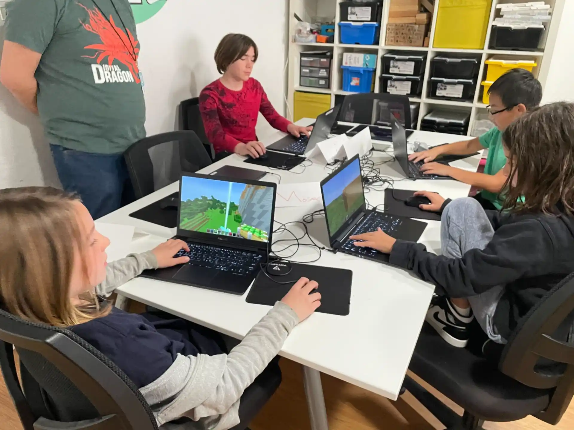 a group of people sitting at a table with laptops