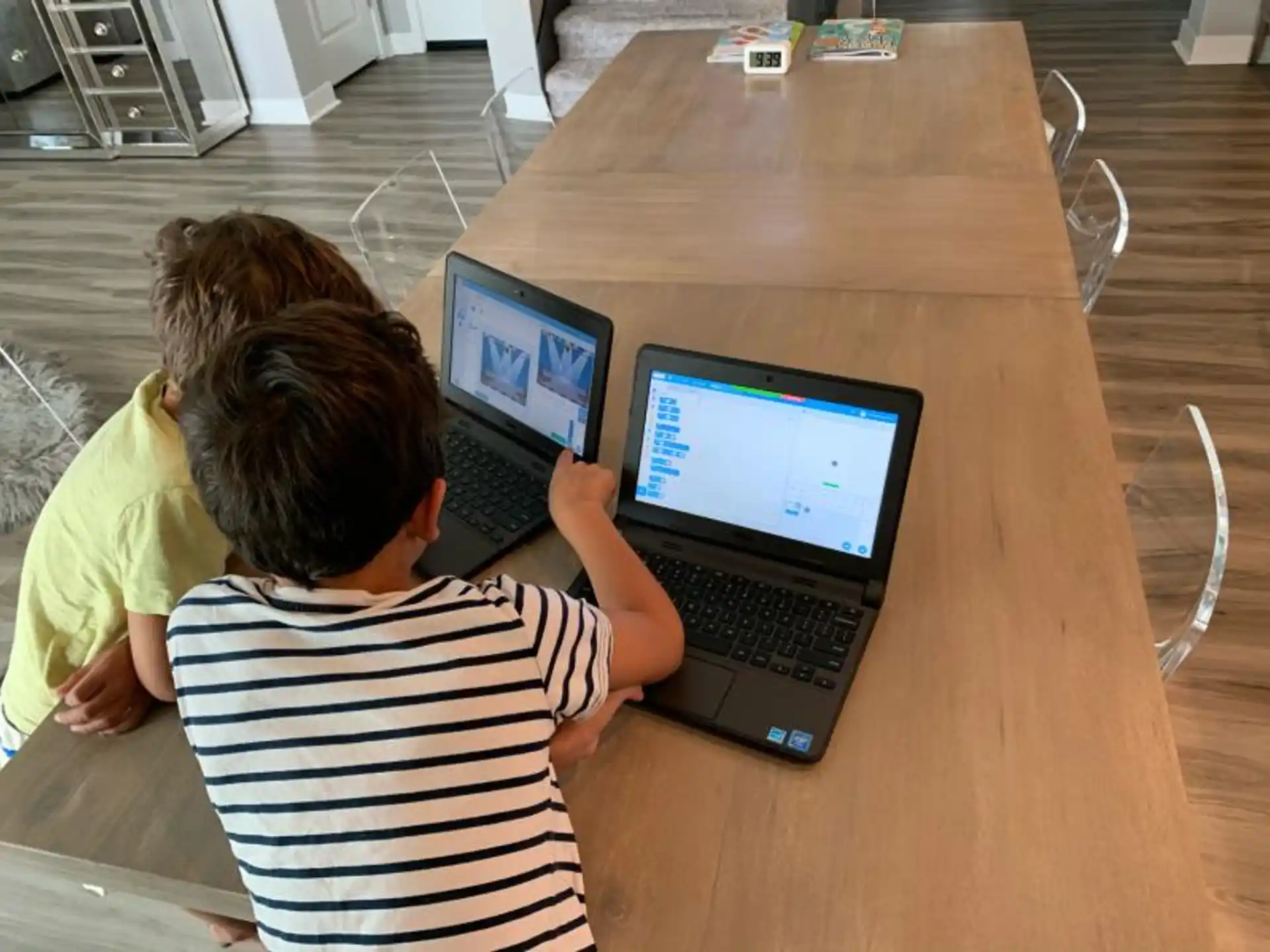 a couple of people sit at a table with laptops
