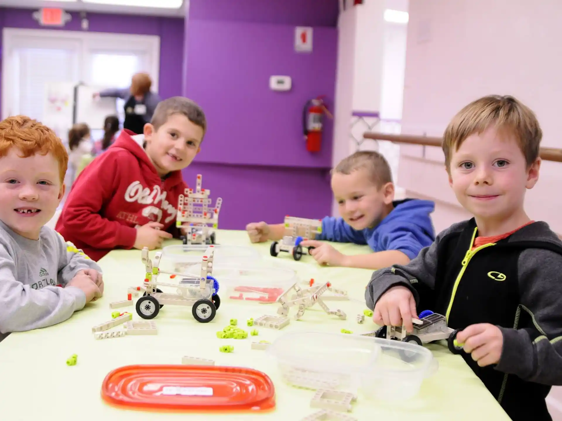 a group of boys sitting at a table with toy cars