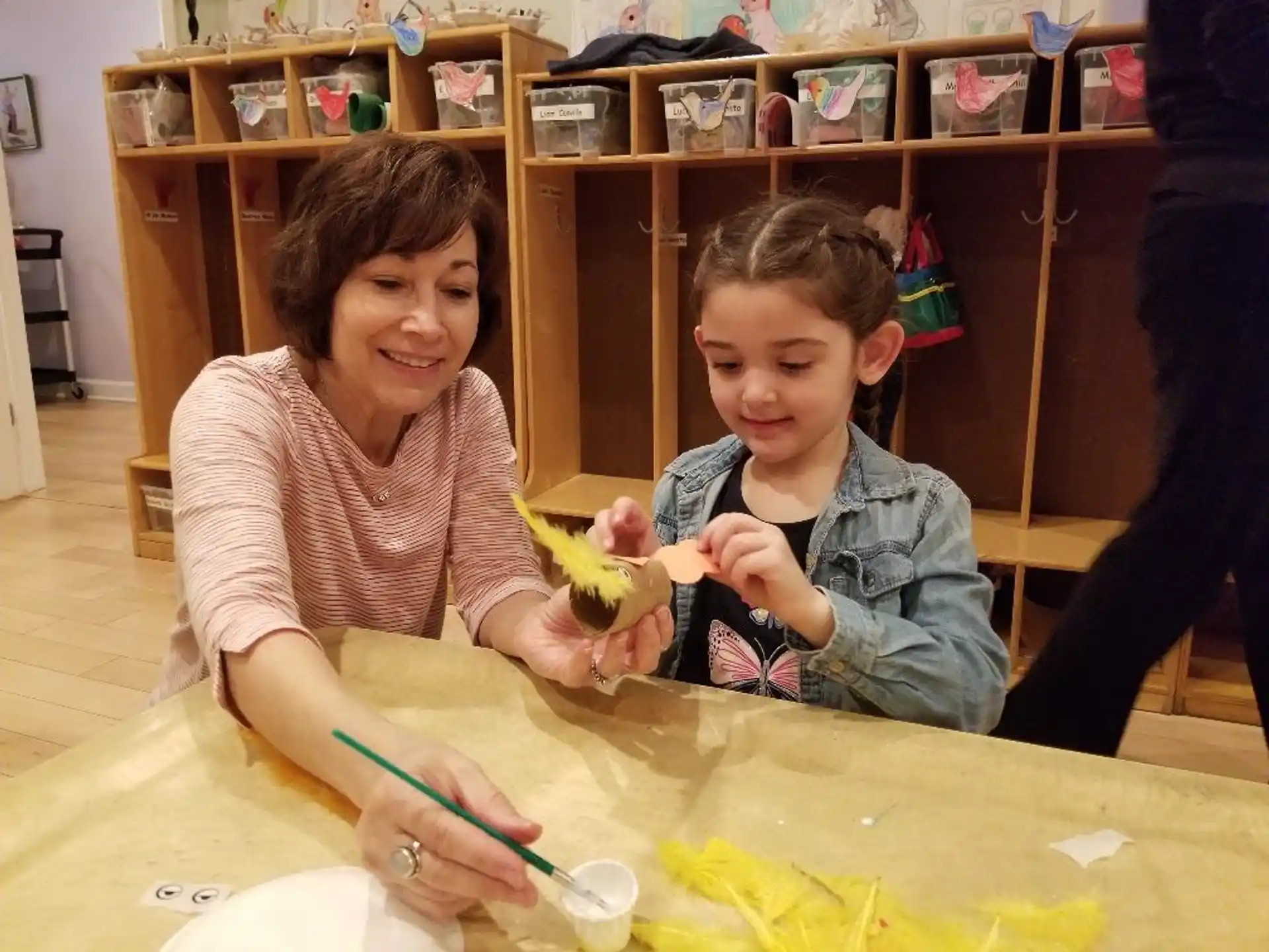 a person and a boy sitting at a table with a yellow toy
