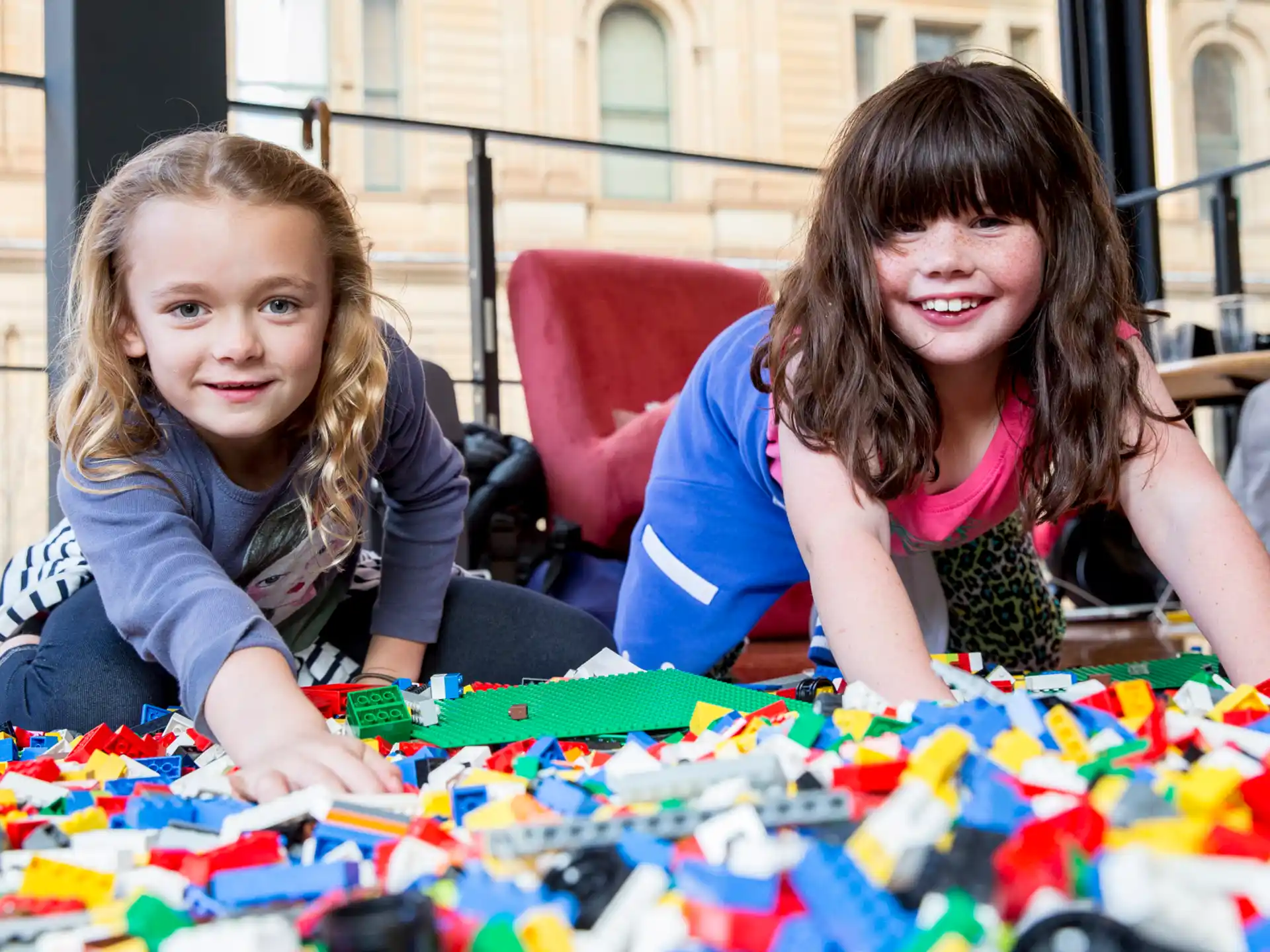 a couple of girls sitting at a table with a board game