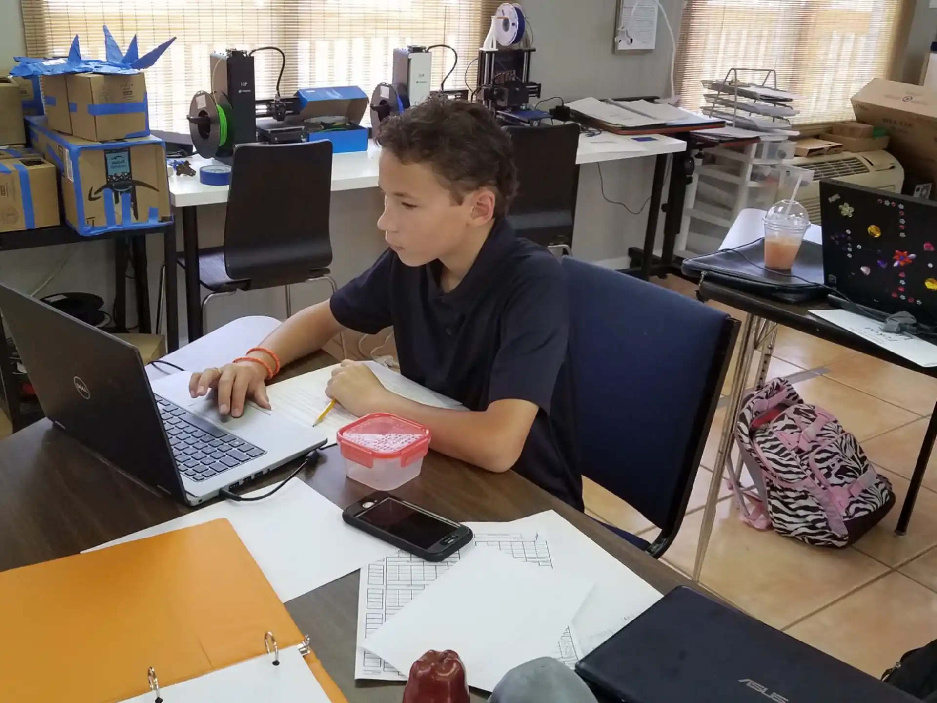 a boy sitting at a desk with a laptop