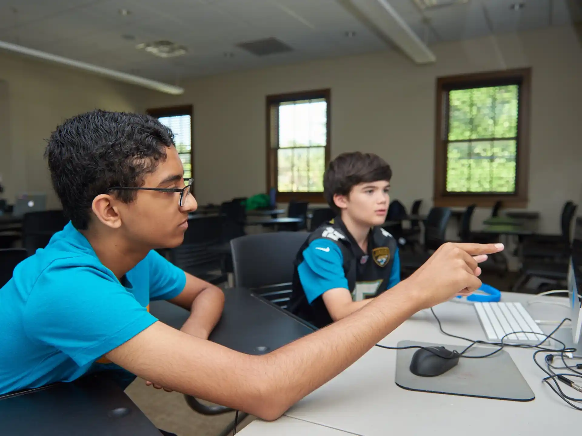 a man and a boy sitting at a table looking at a computer