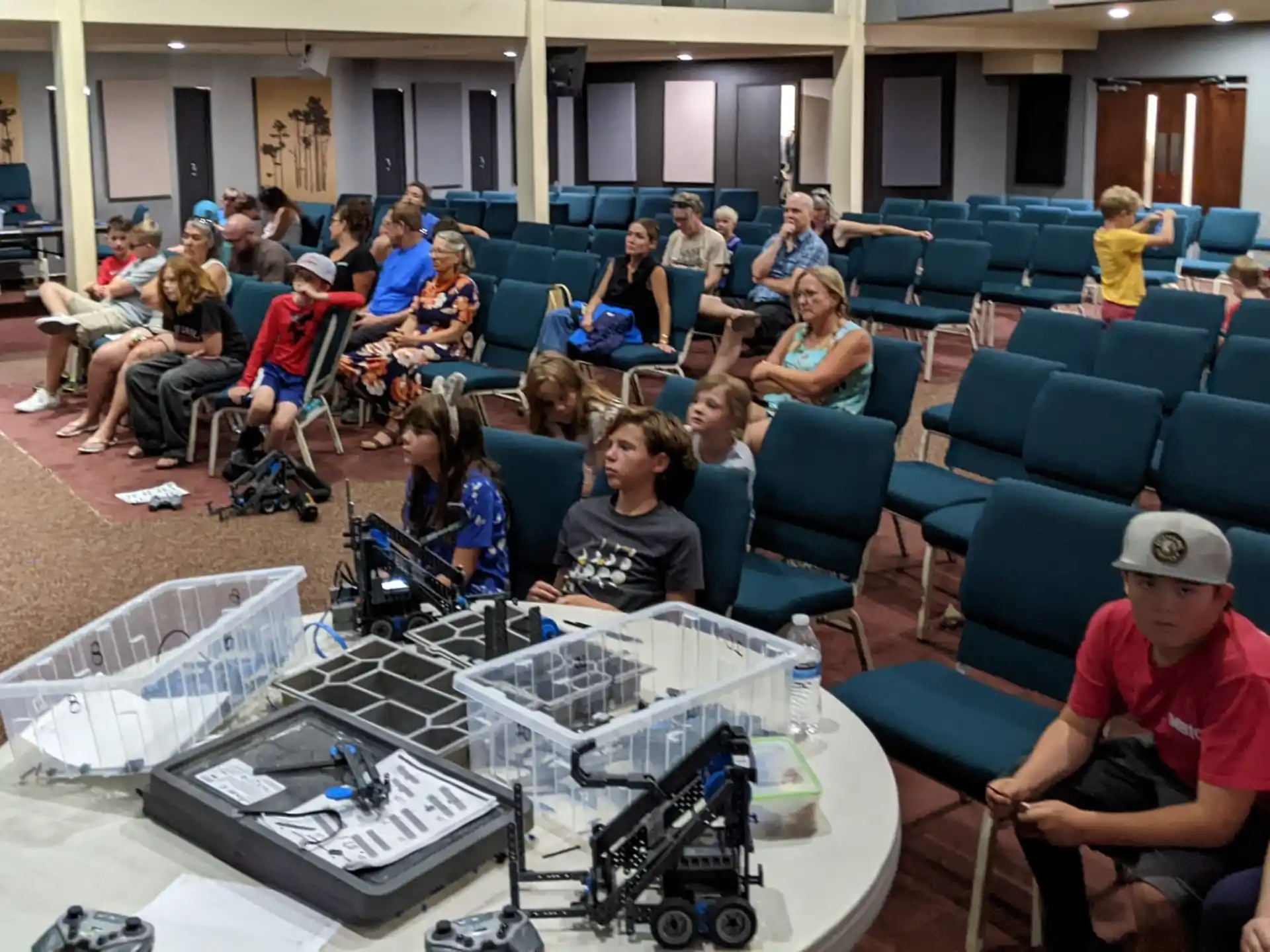 a group of people sitting in a room with a table and a camera