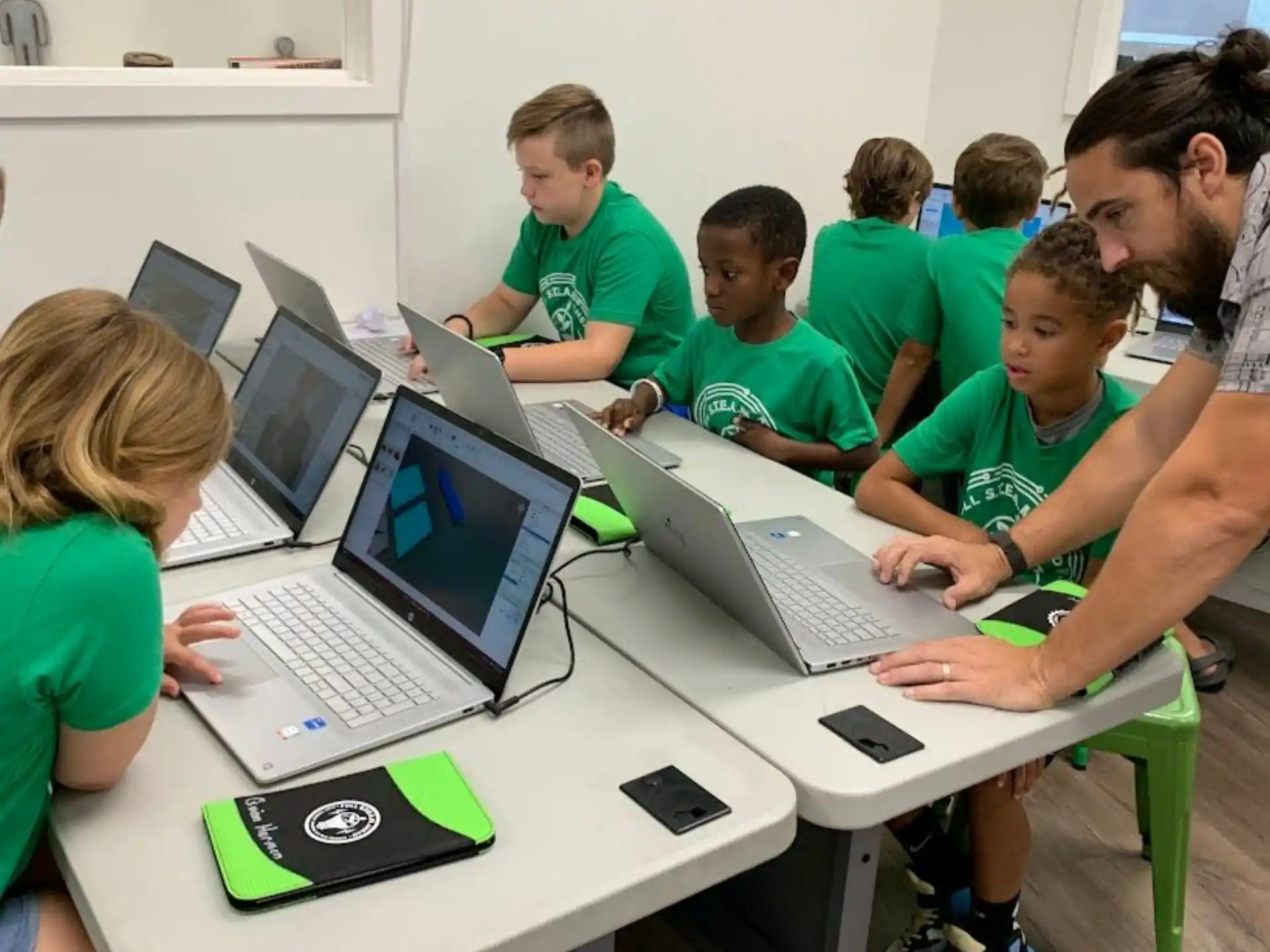 a group of people sitting at a table with laptops