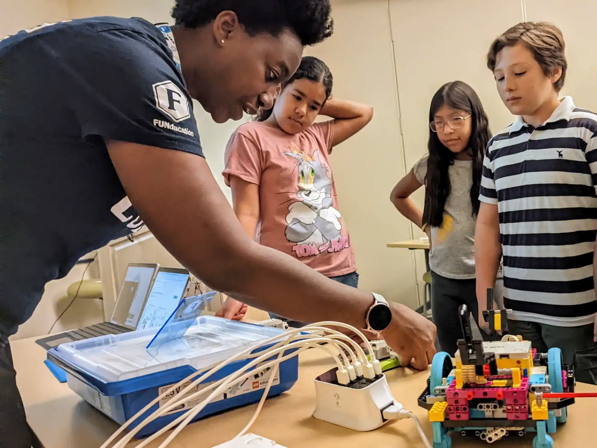 a man showing a group of kids something on a computer