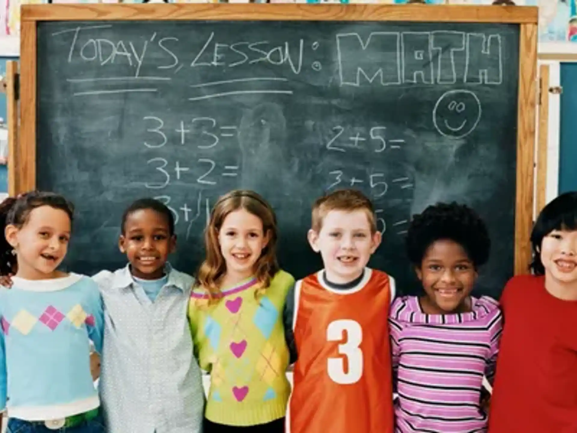 a group of children posing for a photo in front of a chalkboard