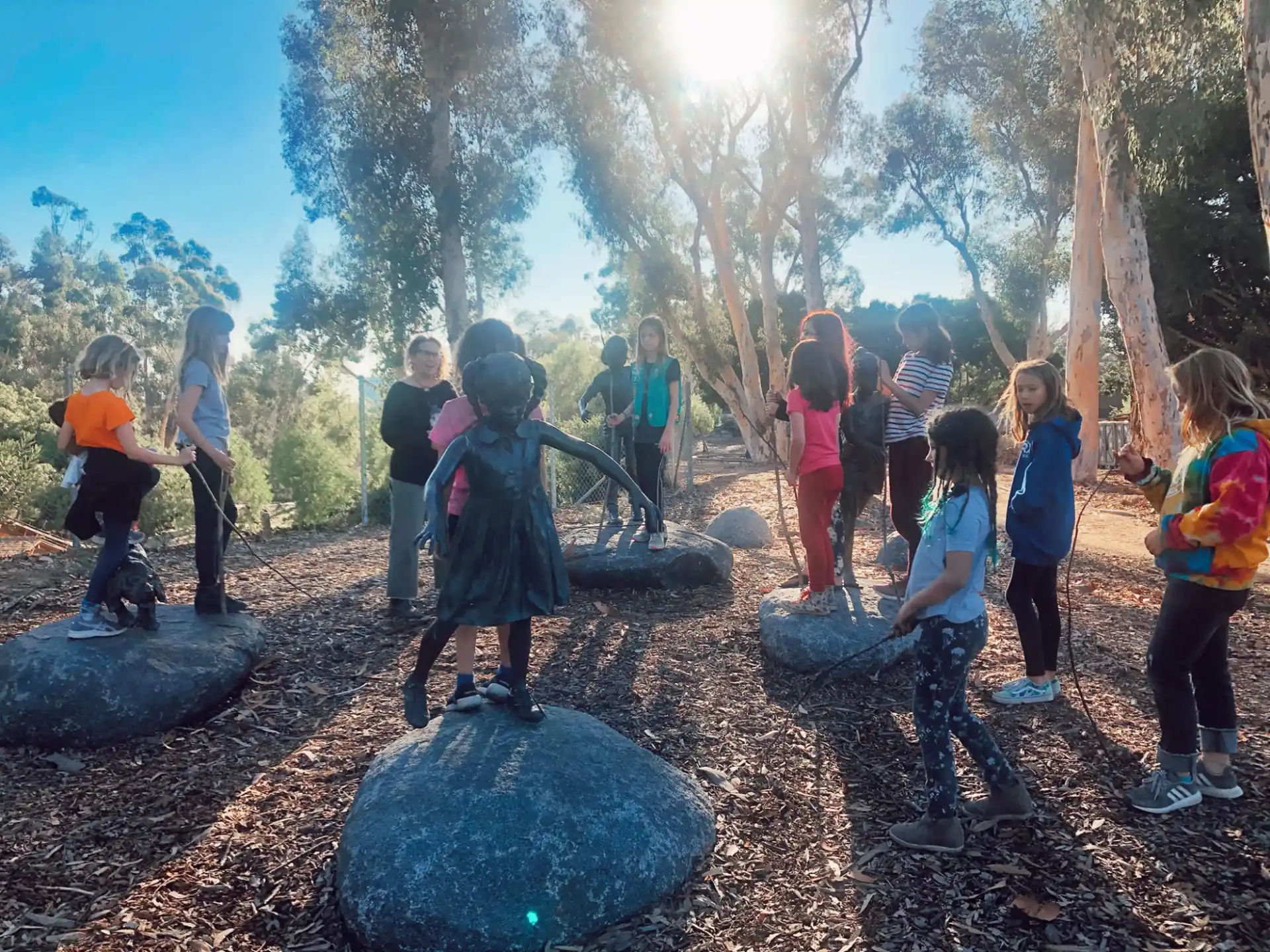 a group of children playing with a statue in a forest