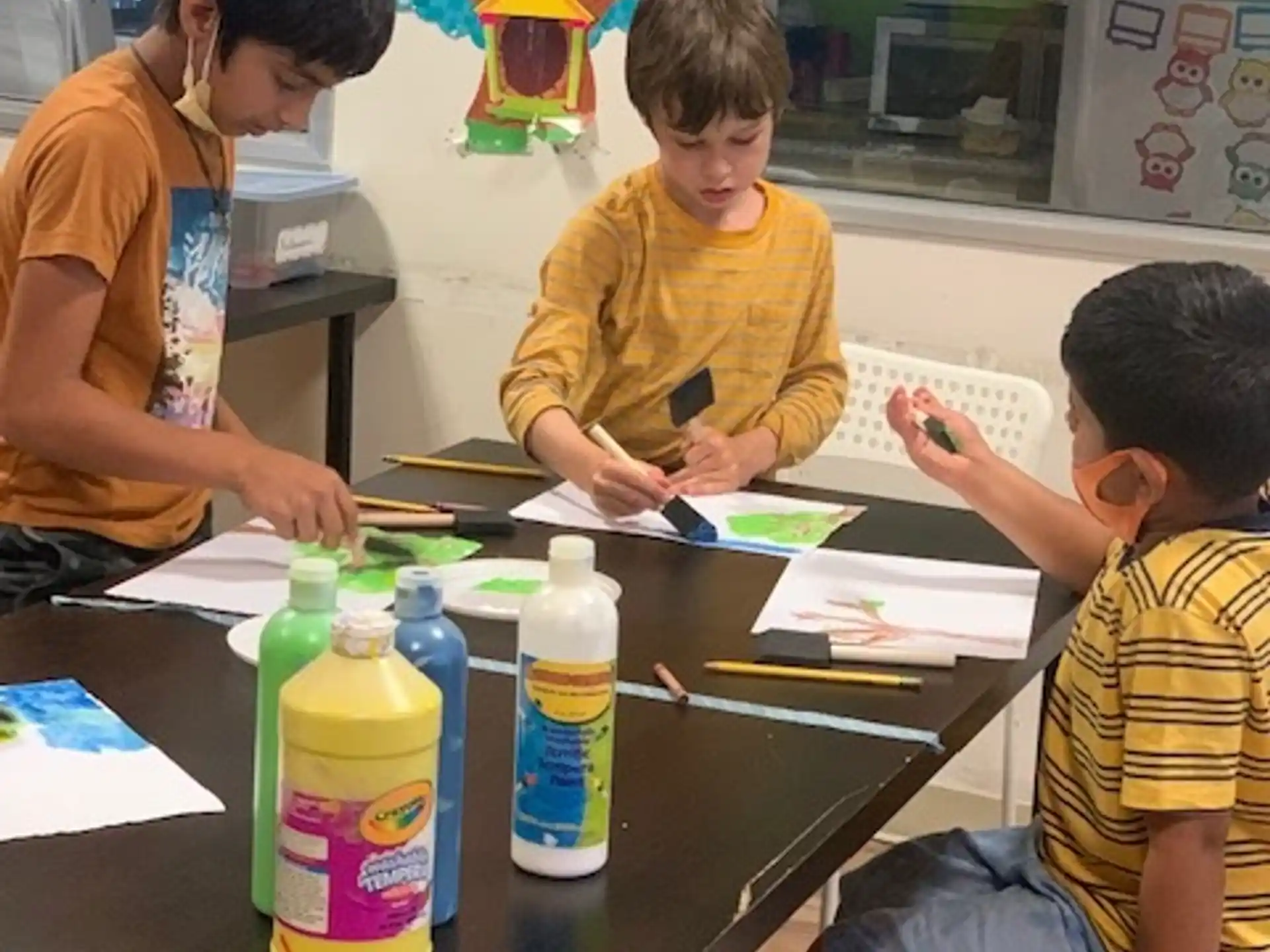a group of boys sitting at a table in a classroom