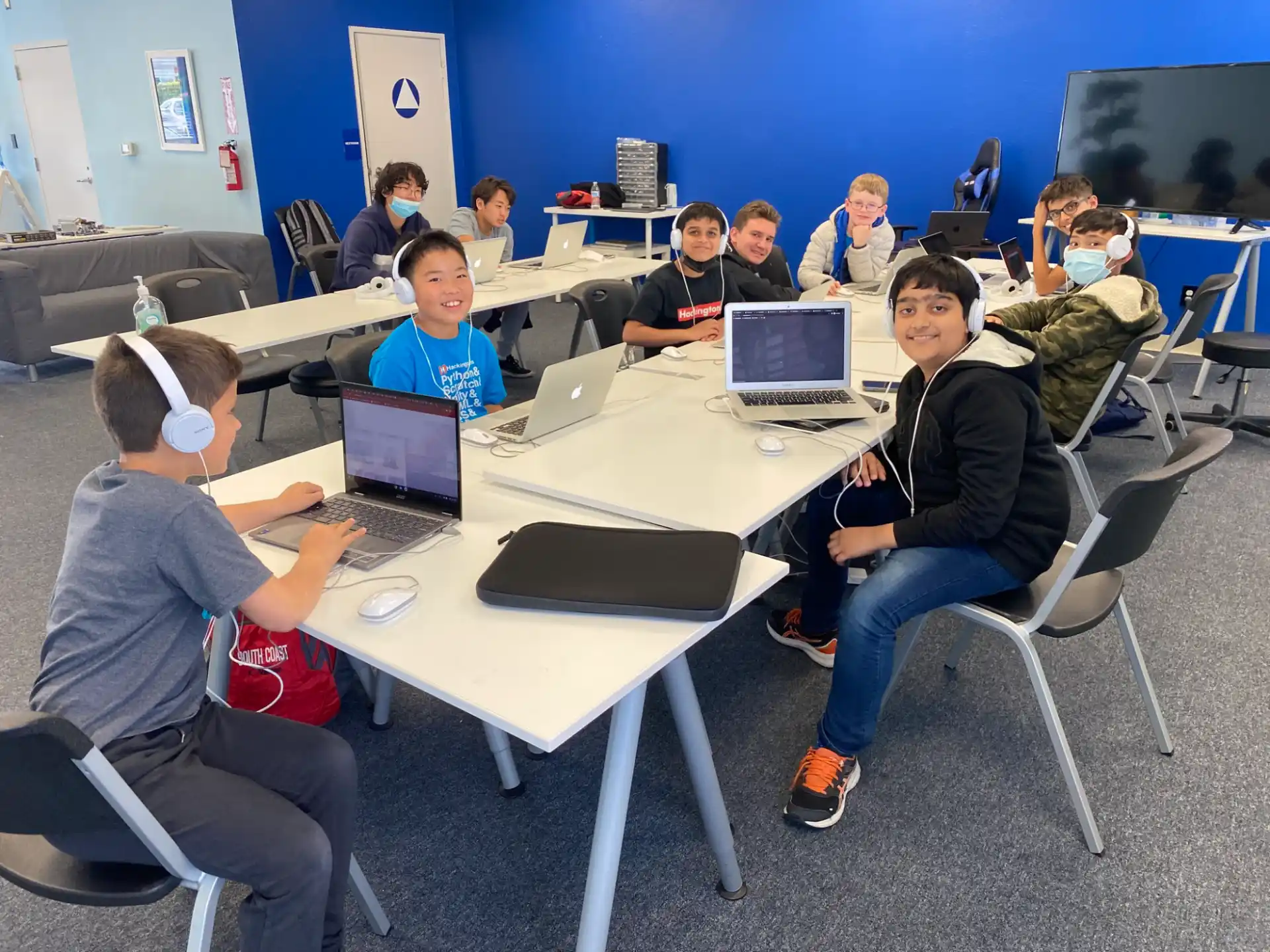 a group of people sitting at a table with laptops