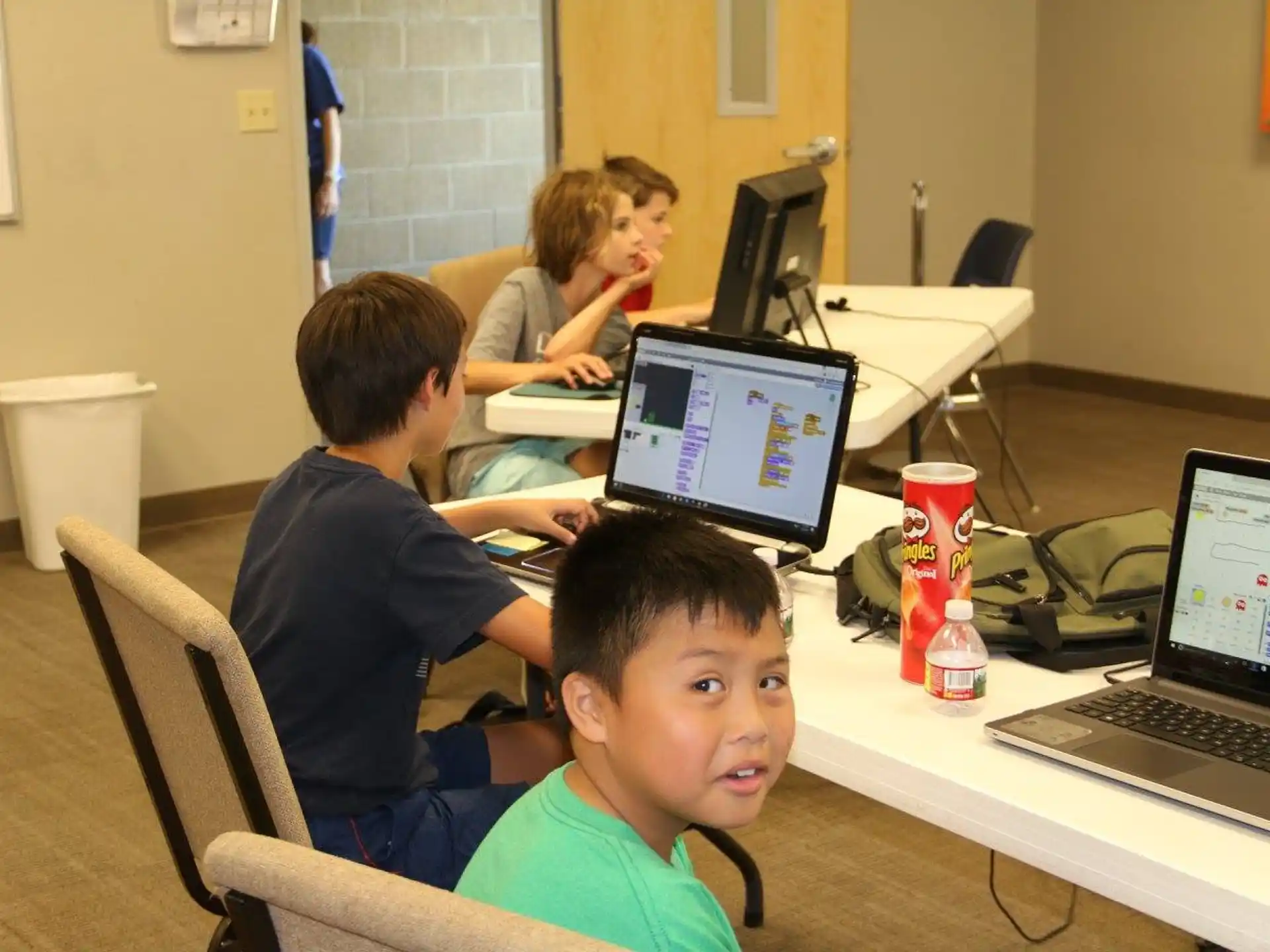 a group of people sitting at a table with laptops