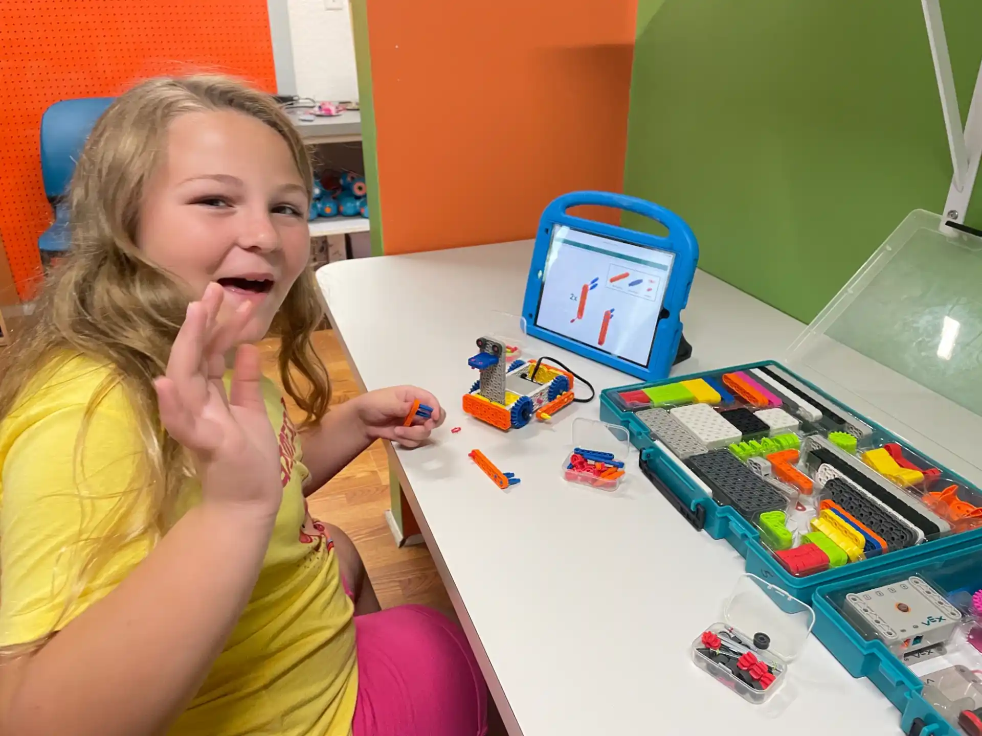 a girl sitting at a table with toys on it