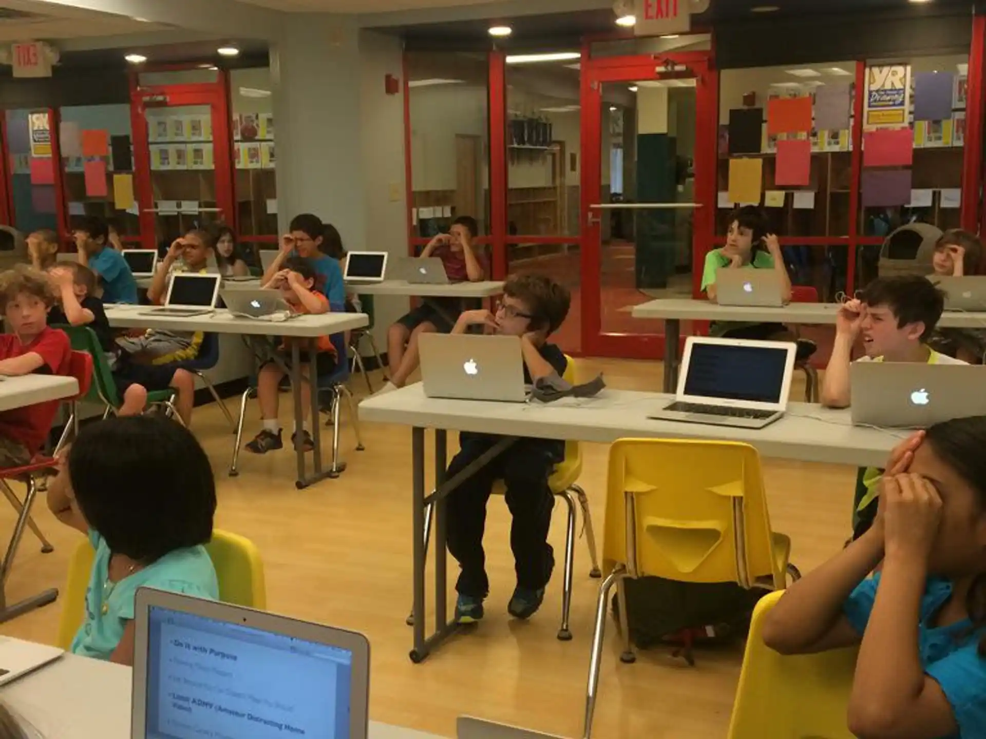 a group of children sitting at desks with laptops