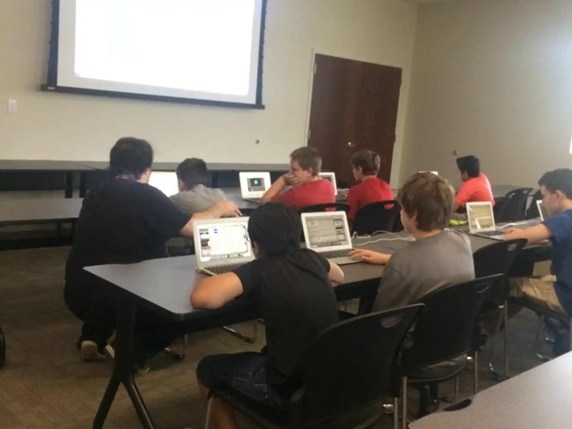 a group of people sitting at a table with laptops