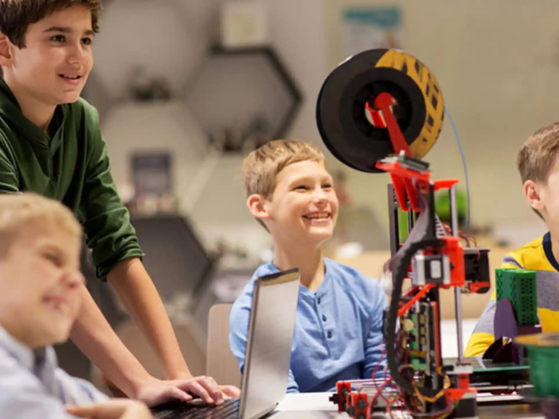 a group of boys sitting at a table with a robot