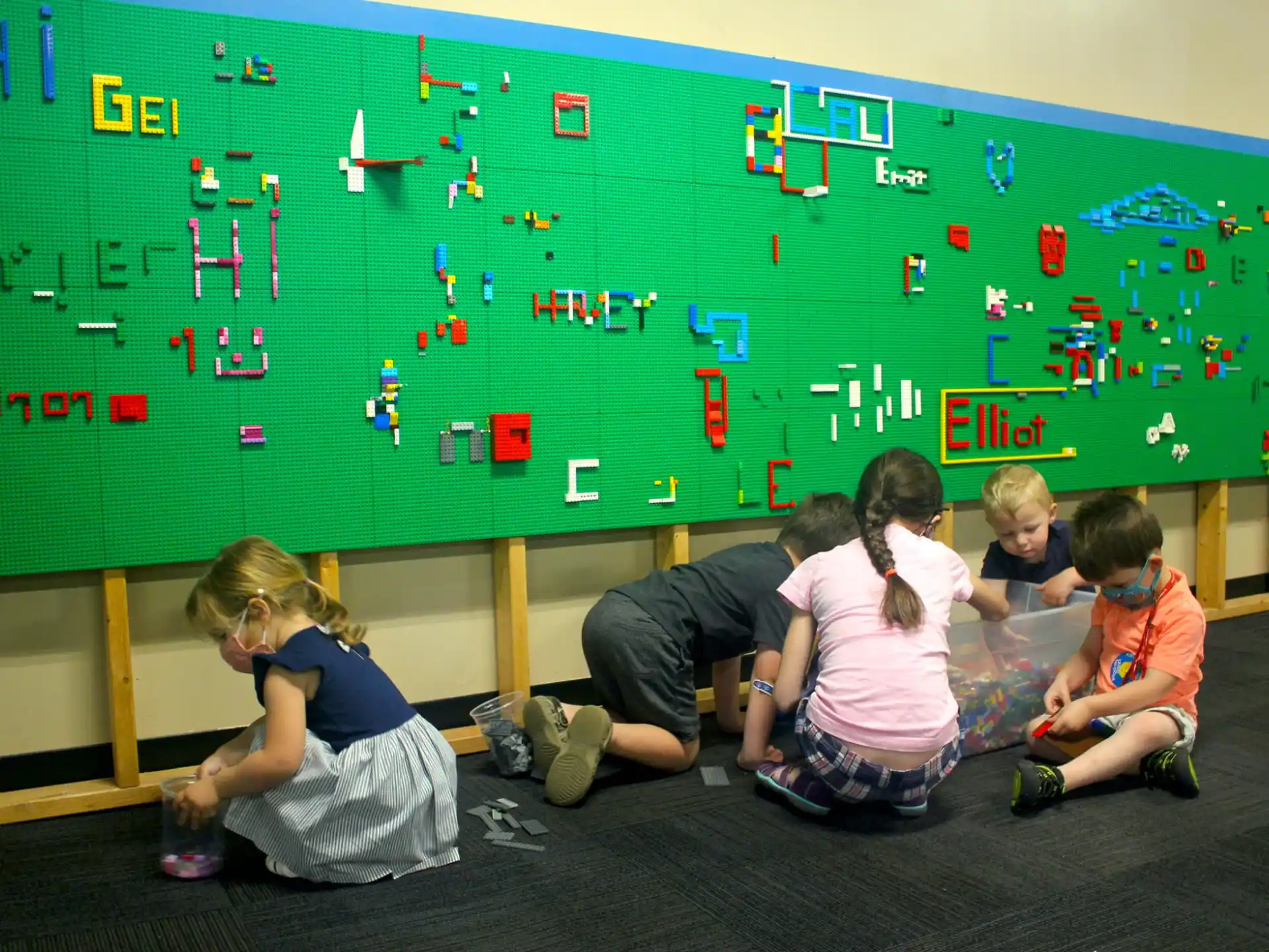 a group of children sitting on the floor in front of a chalkboard