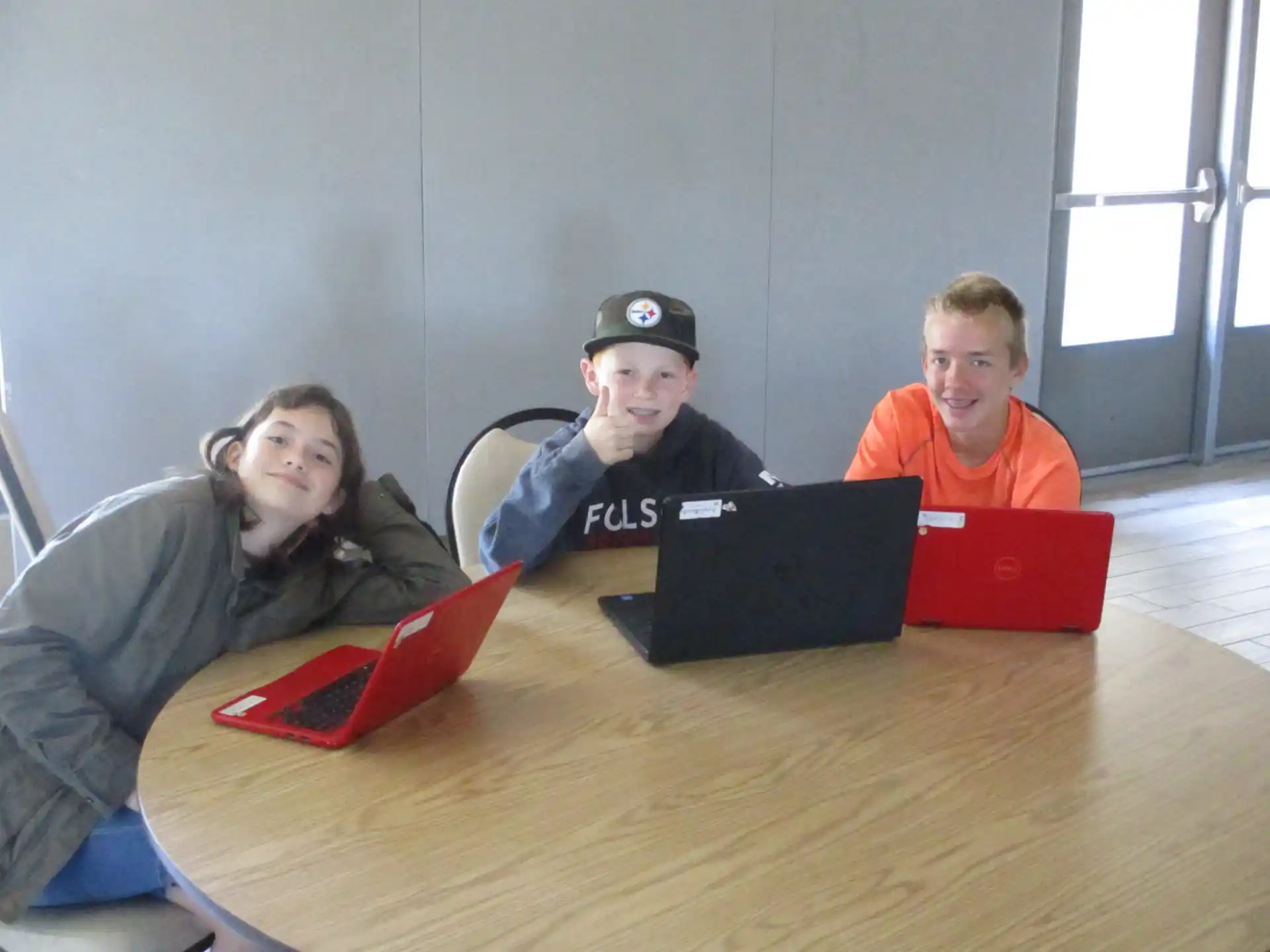 a group of people sitting at a table with laptops