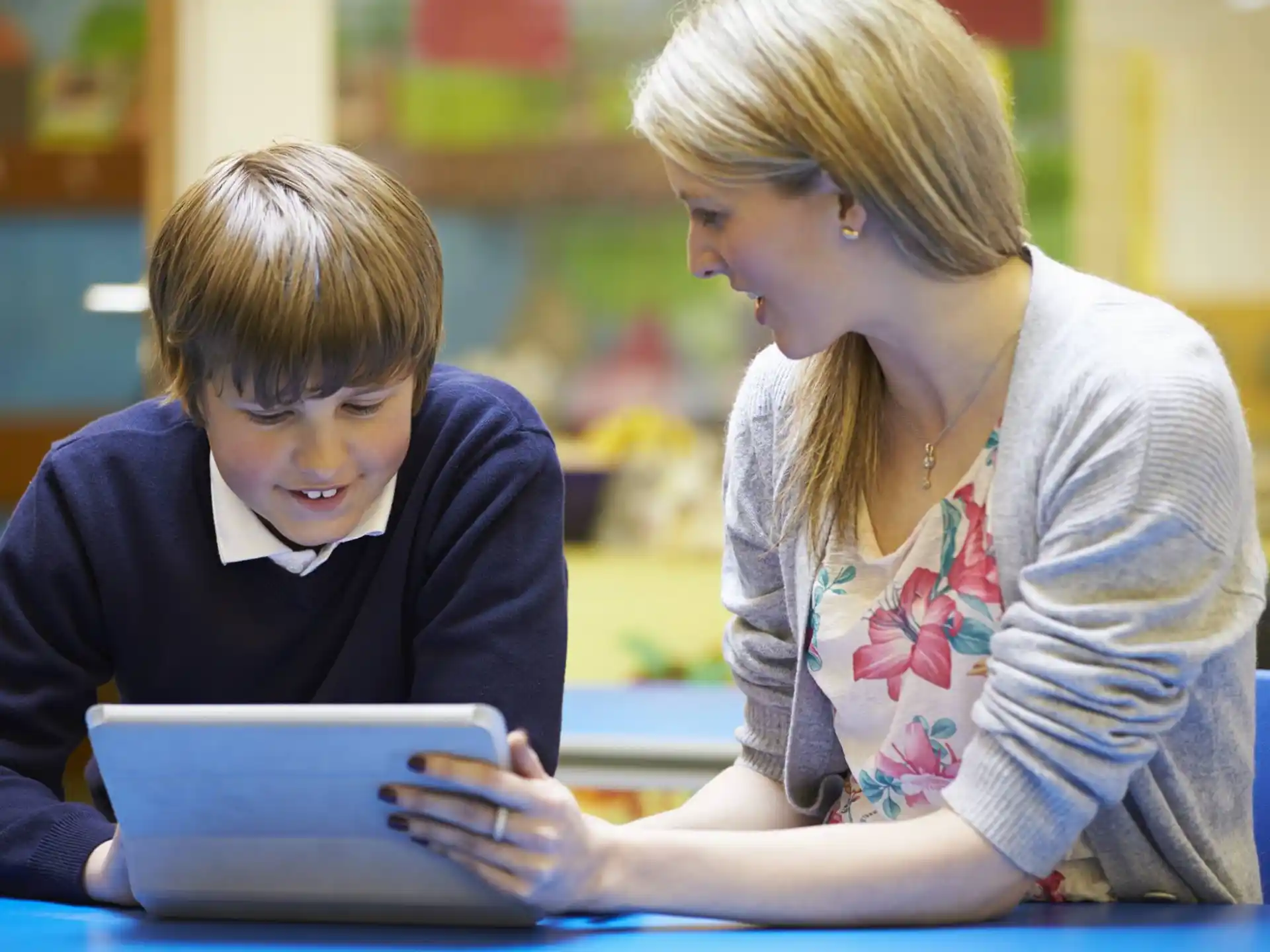 a person and a boy looking at a tablet