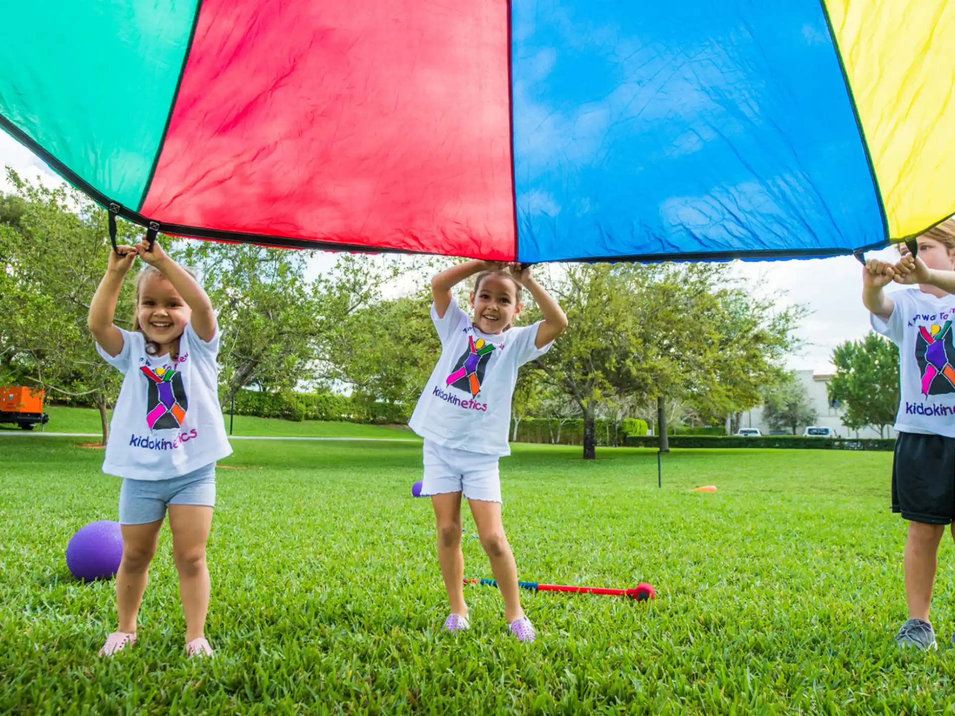a group of kids holding a large colorful kite