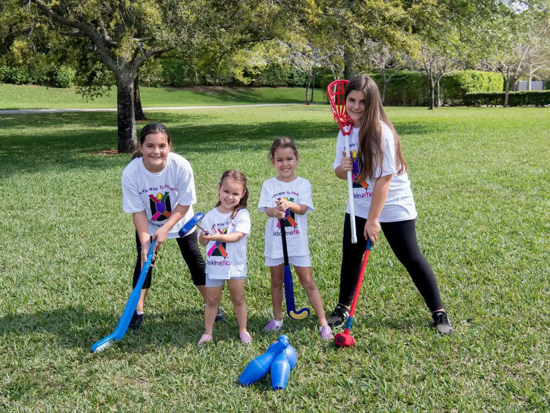 a group of kids playing with toy swords in a grassy area