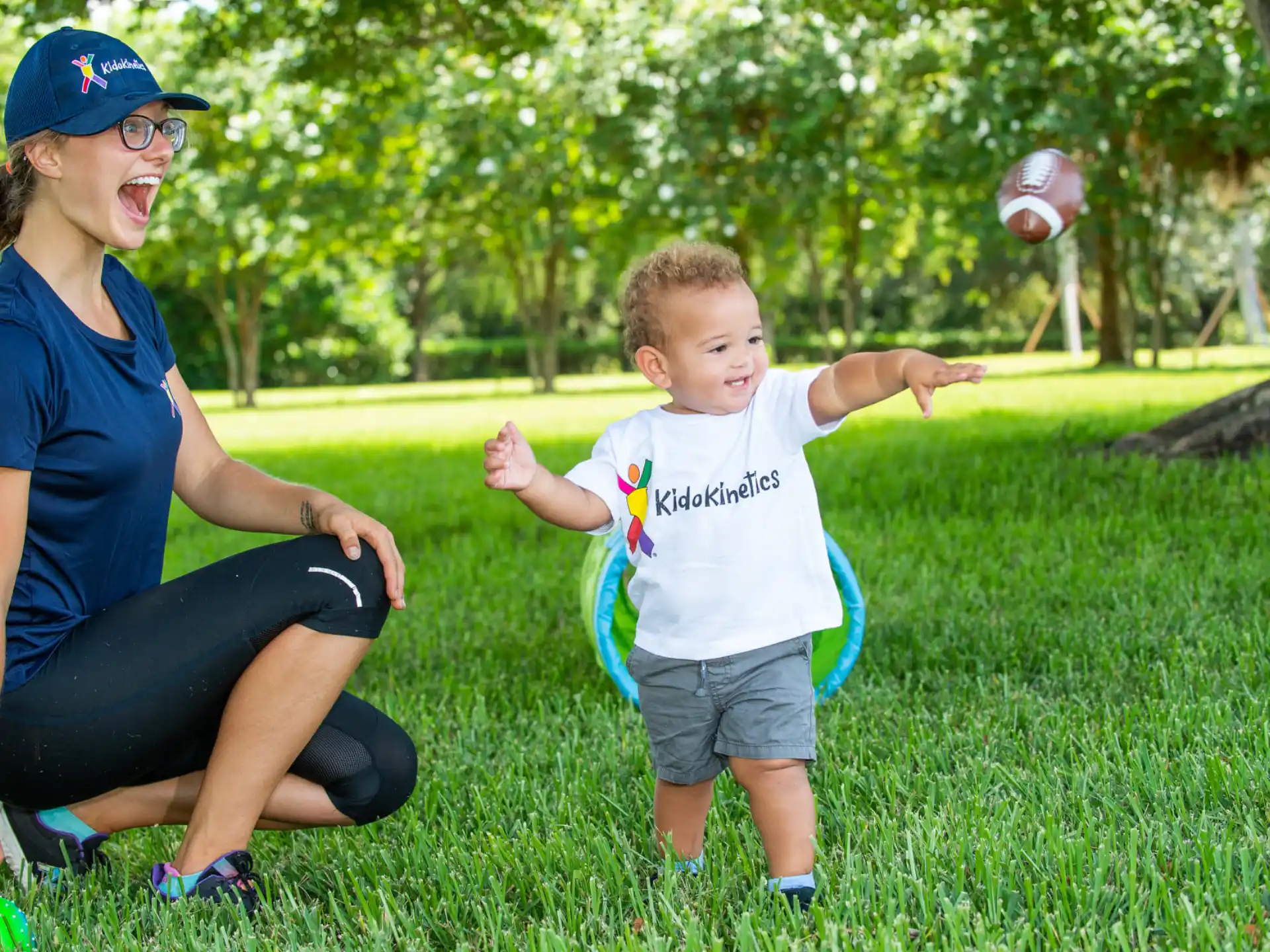 a person and a child playing with a ball in a grassy area