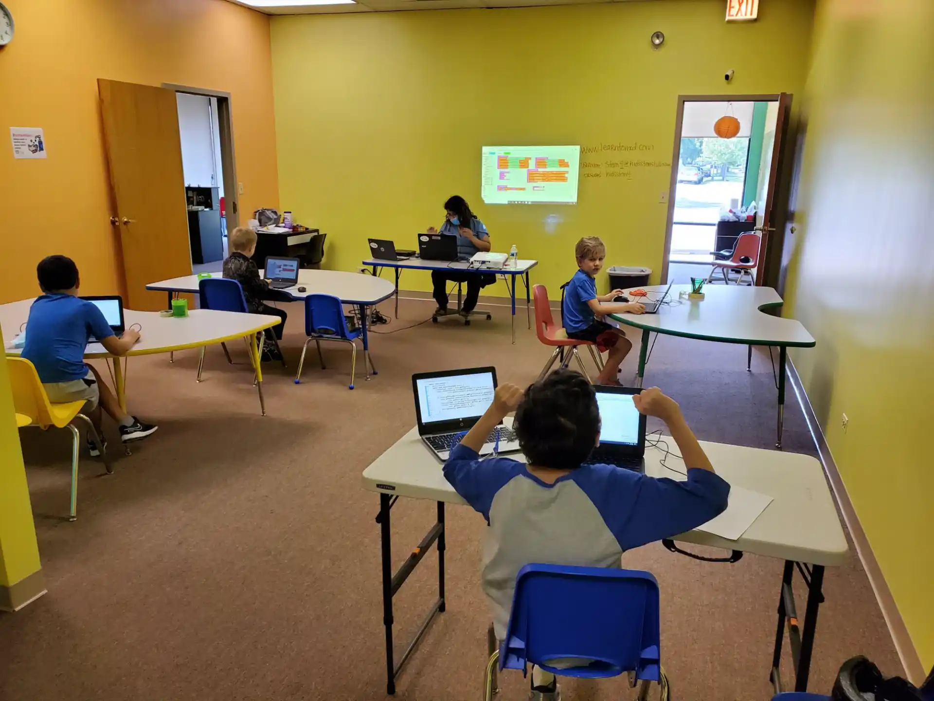 a group of people sitting at tables with laptops
