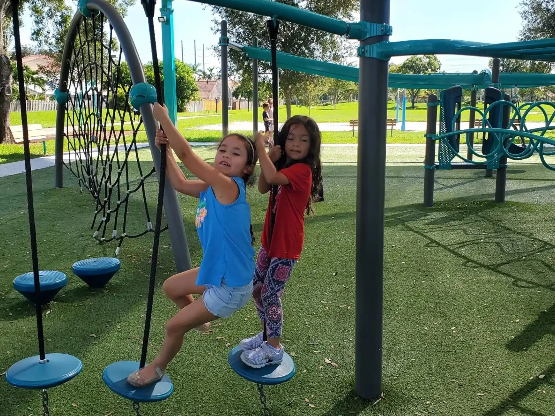 a couple of girls on a swing set in a park