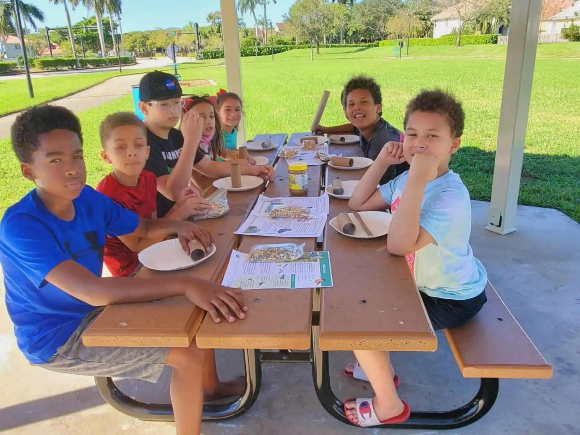 a group of kids sitting at a table outside