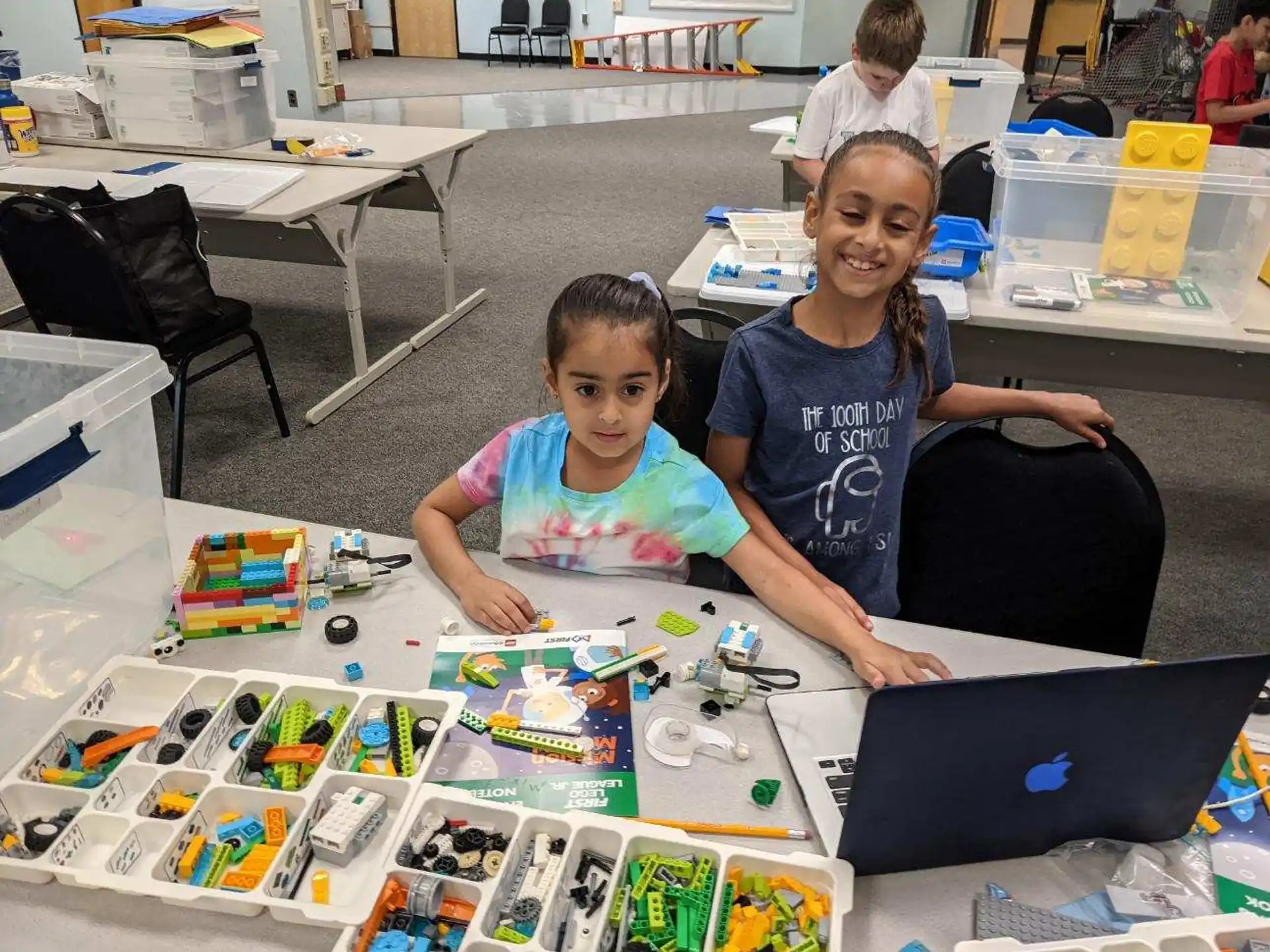 a person and a child sitting at a table with a laptop