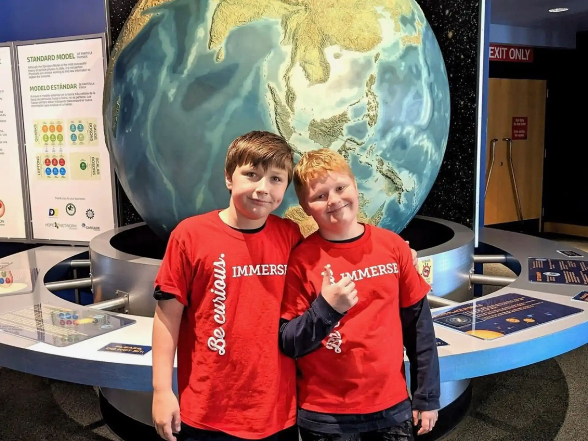 two boys standing in front of a large sculpture