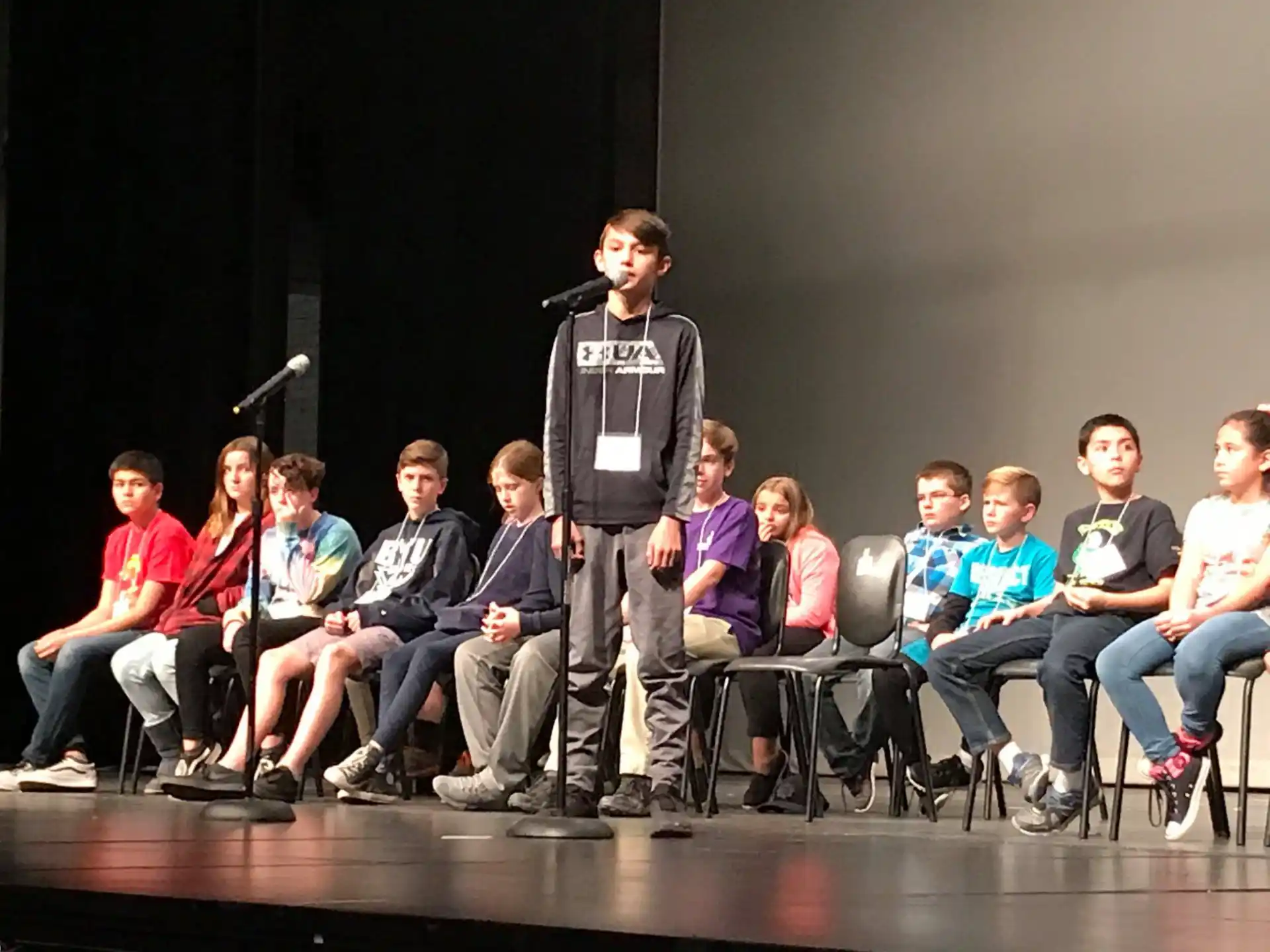a man standing on a stage with a microphone in front of a group of people