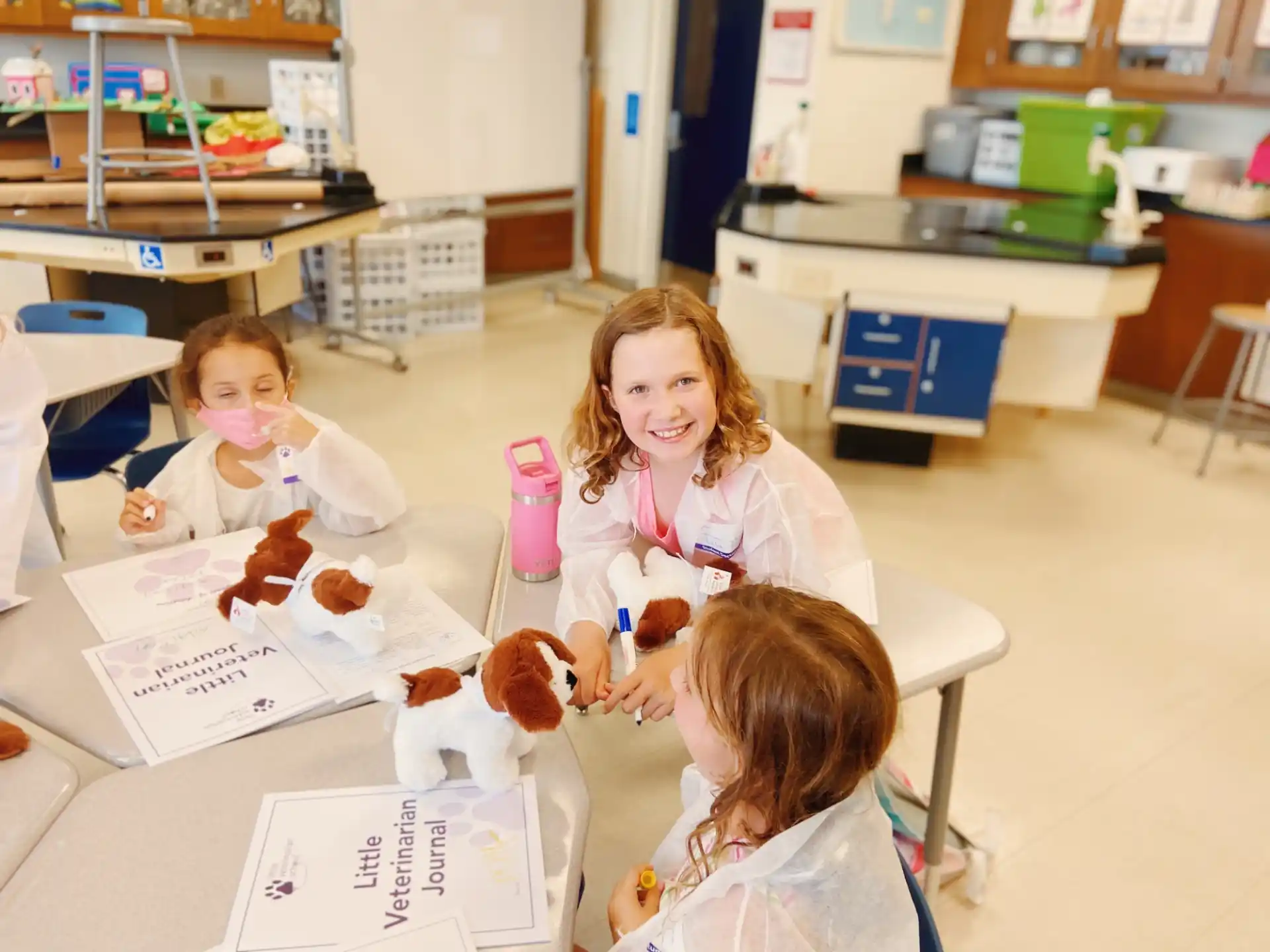 a person and two children sitting at a table with donuts