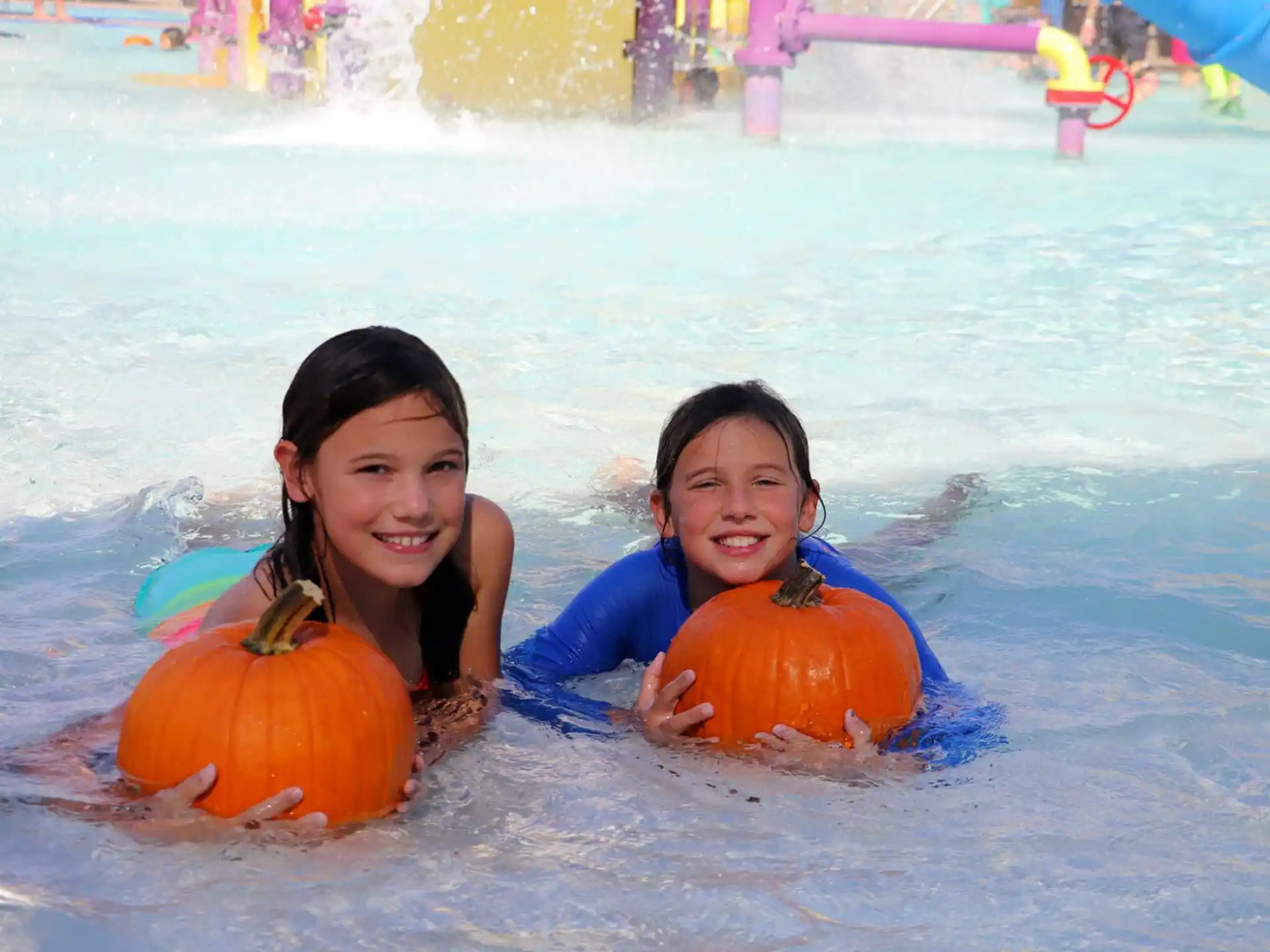 a couple of women in a pool with pumpkins
