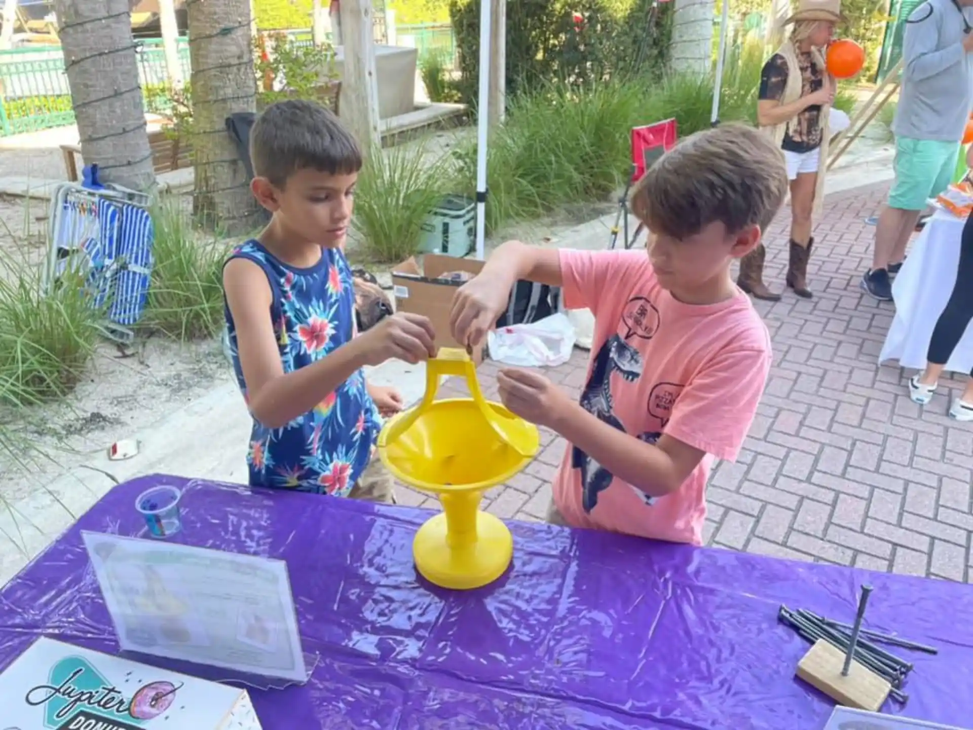 a couple of young boys playing with a yellow watering can