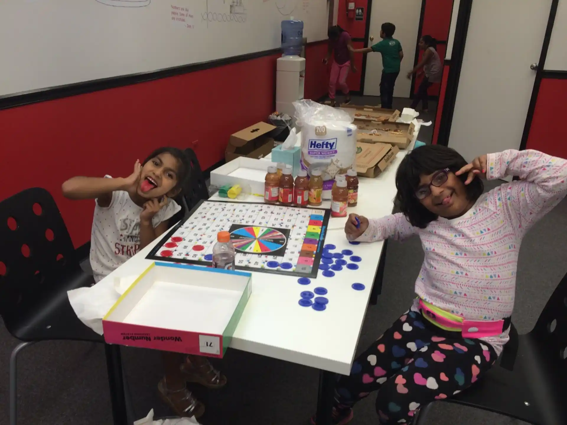 a couple of girls sitting at a table with a board game