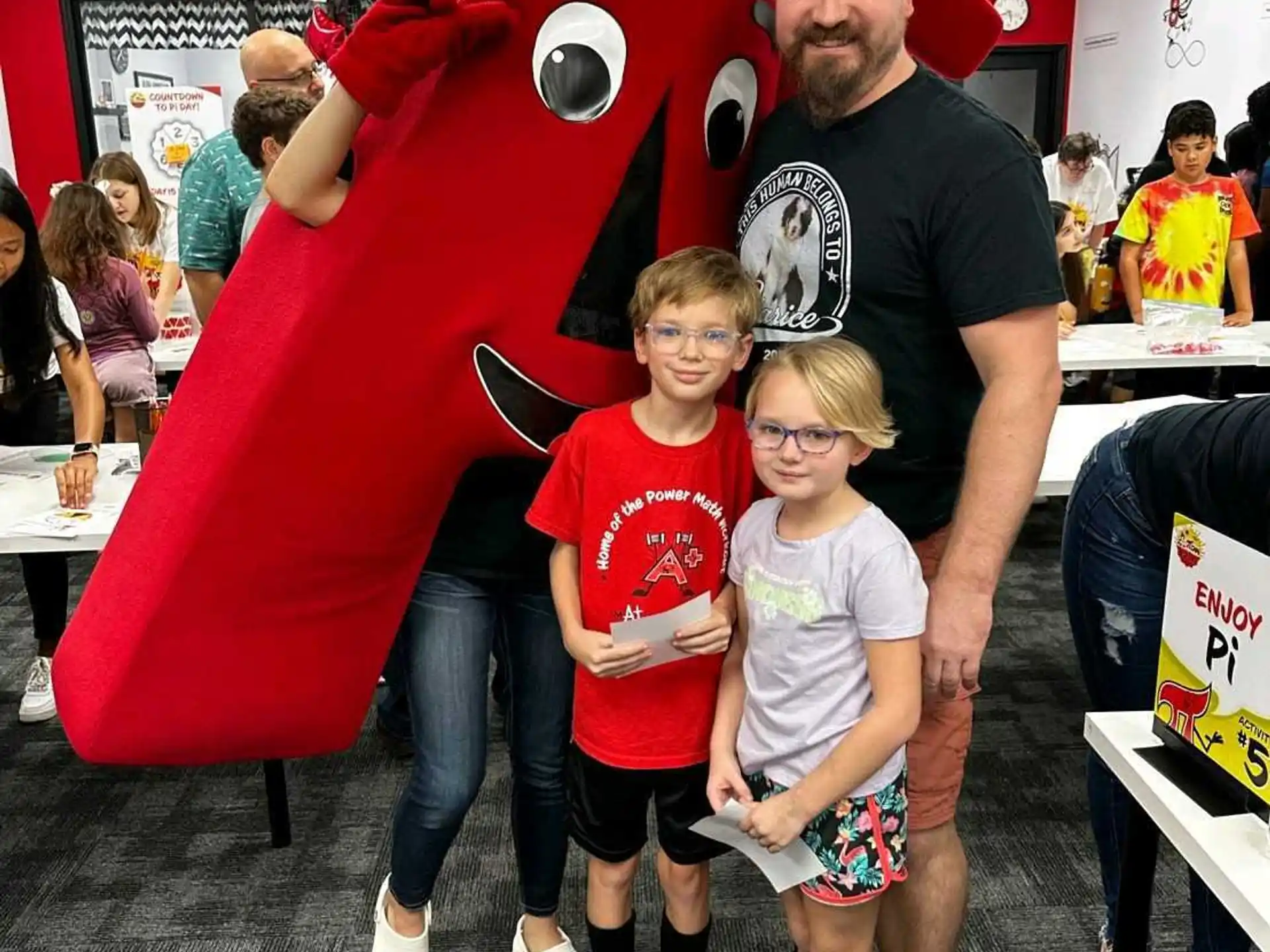 a man and two children posing for a photo in front of a giant red statue