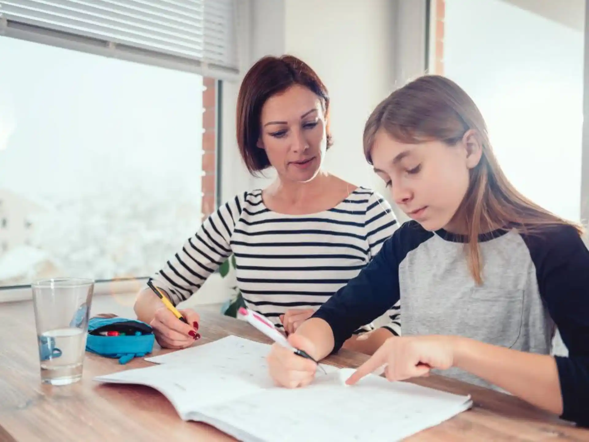 a woman and a girl writing on paper