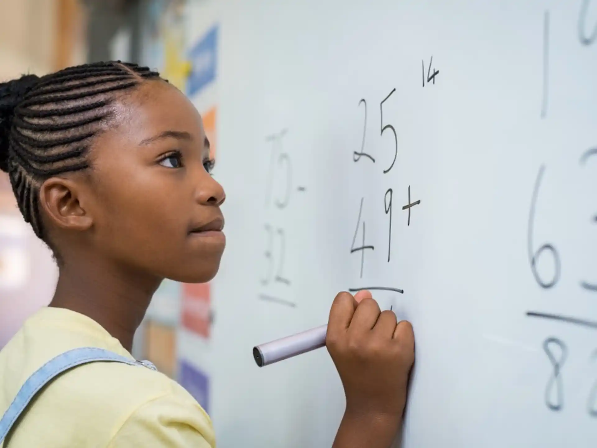 a young girl writing on a whiteboard