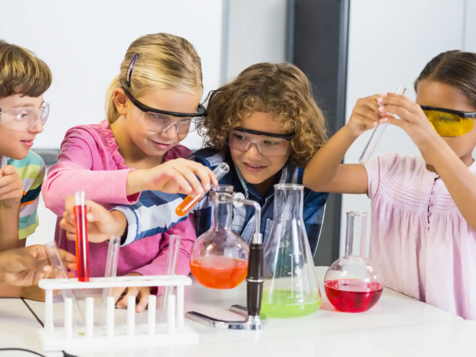 a group of kids wearing safety goggles and looking at a test tube
