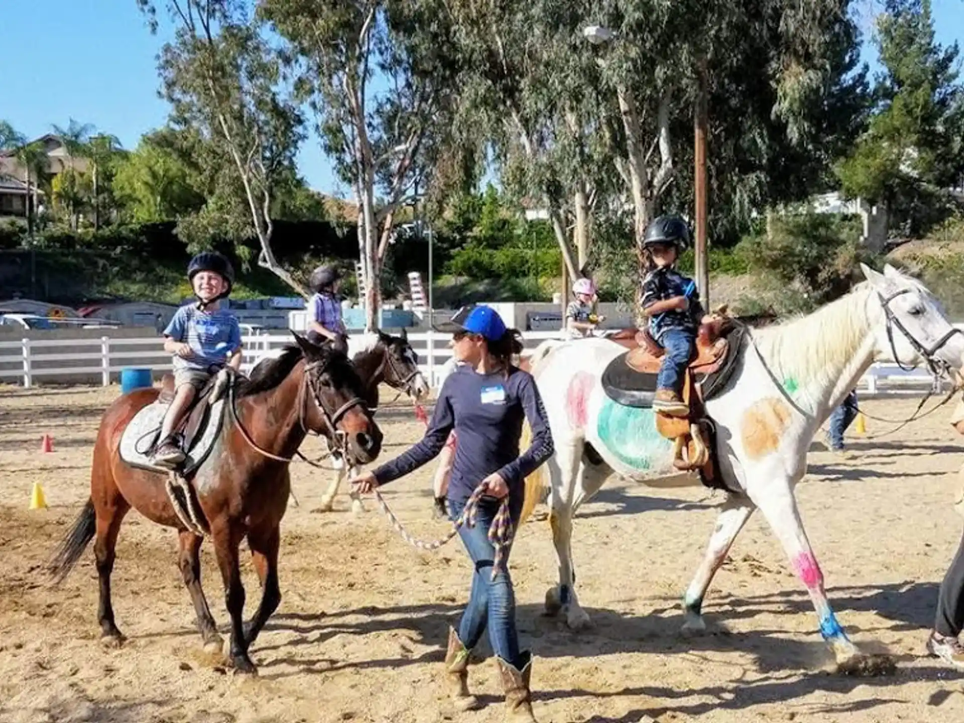 a person leading a group of kids on horses