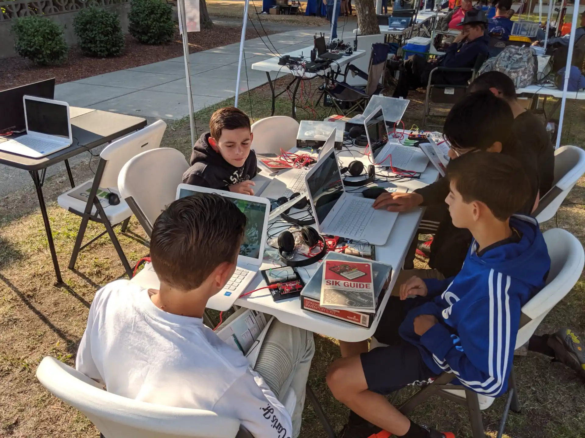 a group of people sitting around a table with laptops