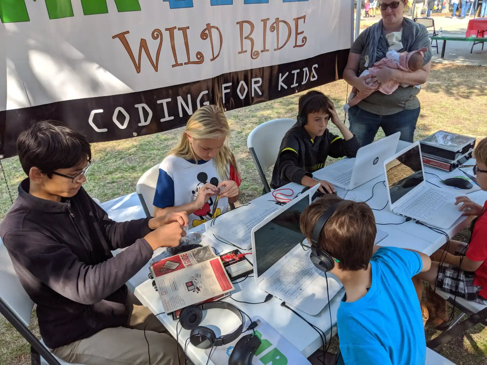 a group of people sitting at a table with books and headphones
