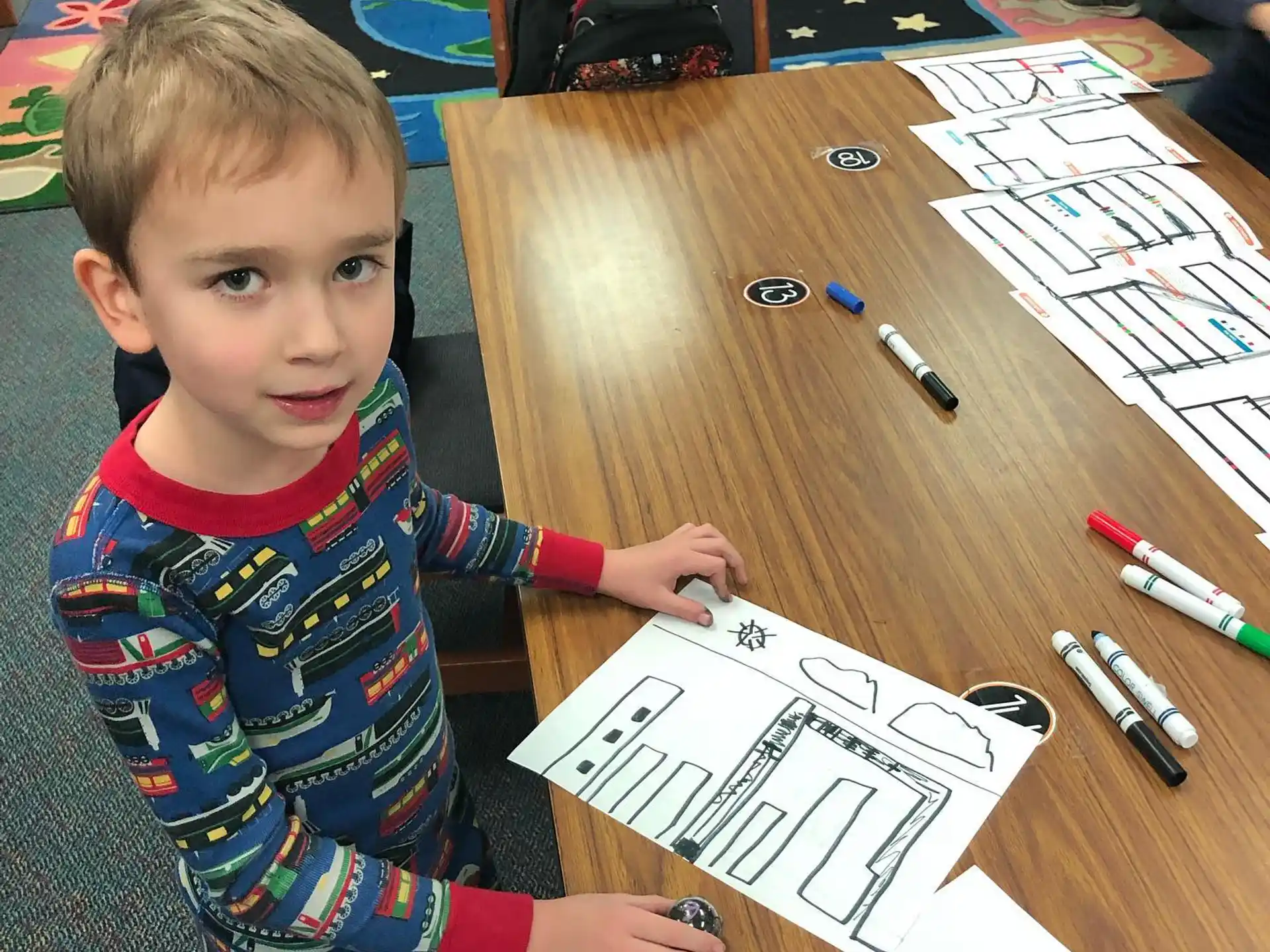 a boy sitting at a table with a drawing on it