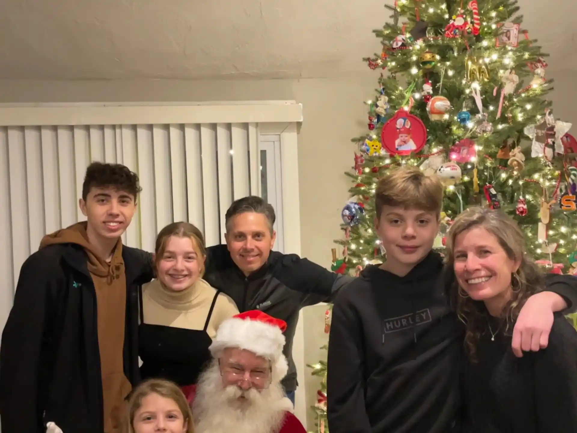 a group of people posing for a photo in front of a christmas tree
