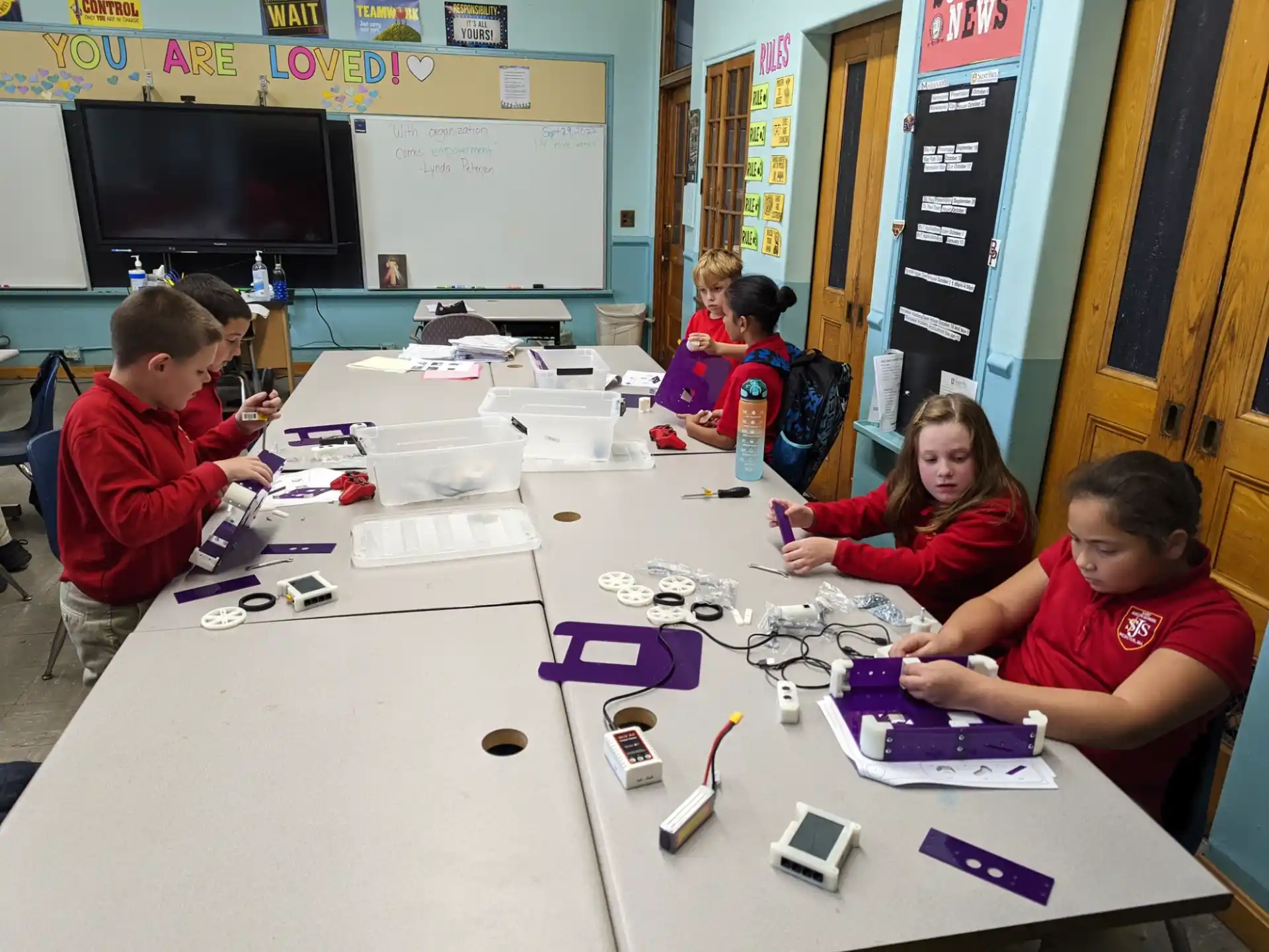 a group of children sitting at a table with papers and pens