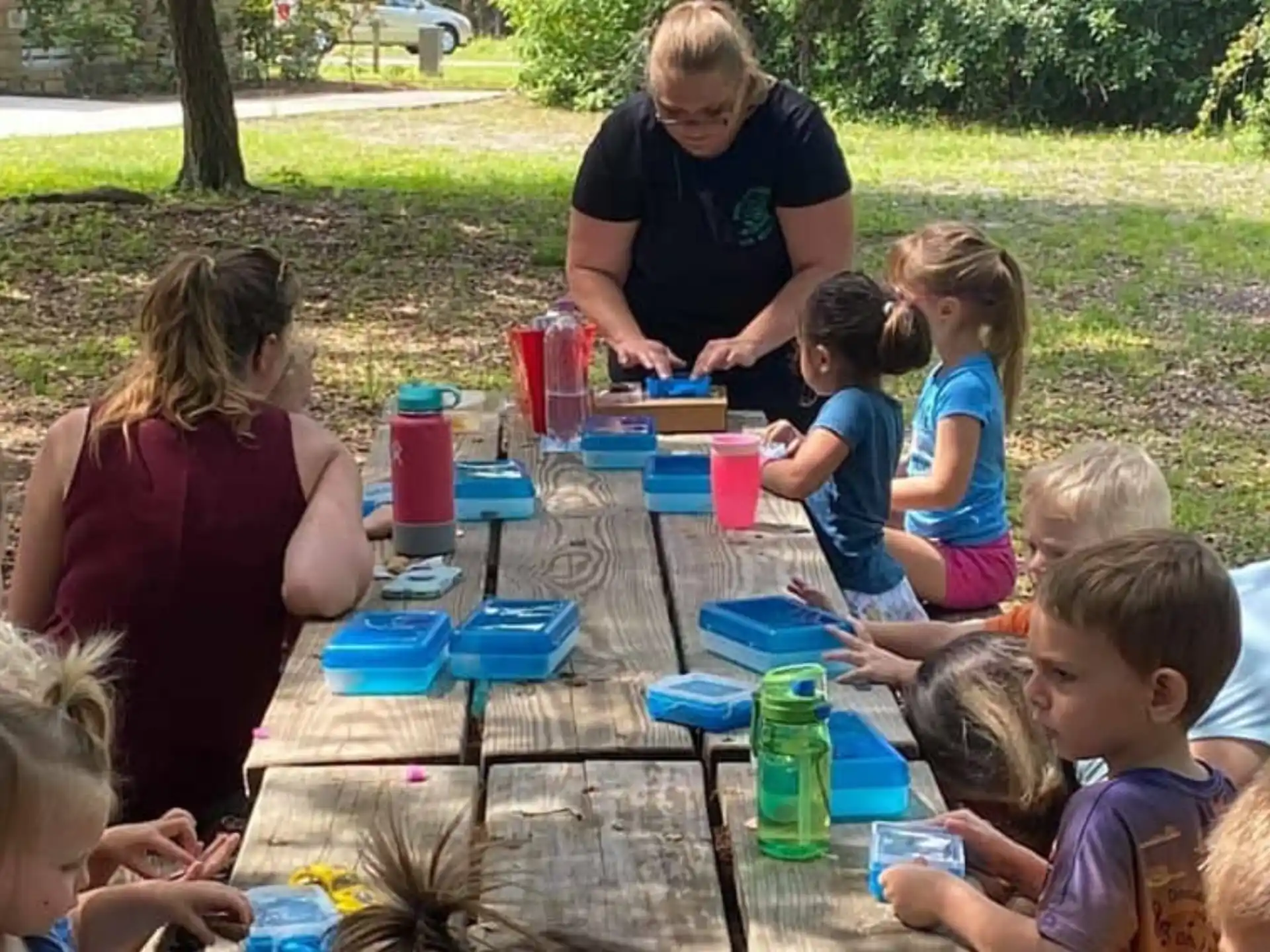 a group of children sitting around a table outside