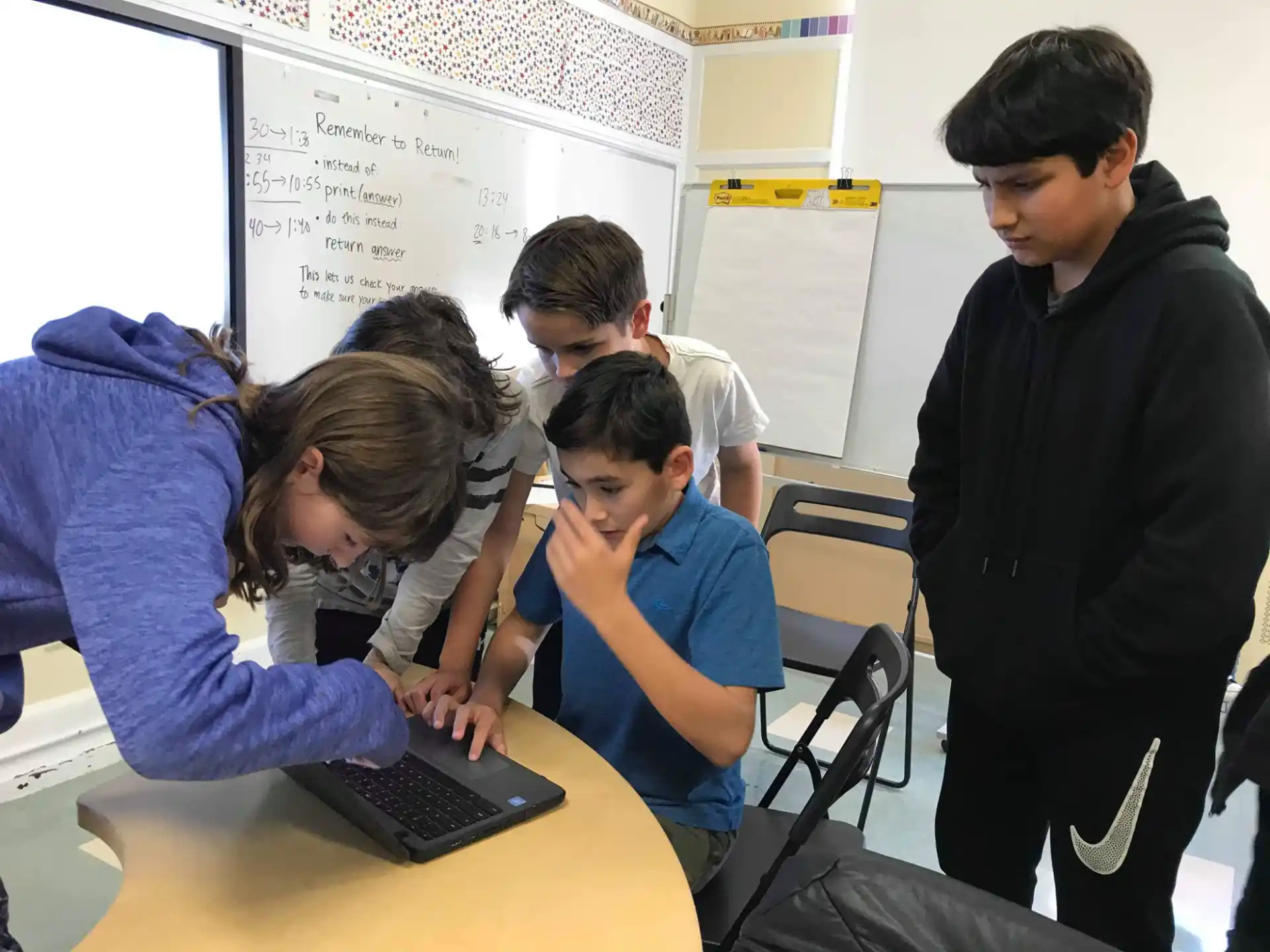 a group of people looking at a laptop