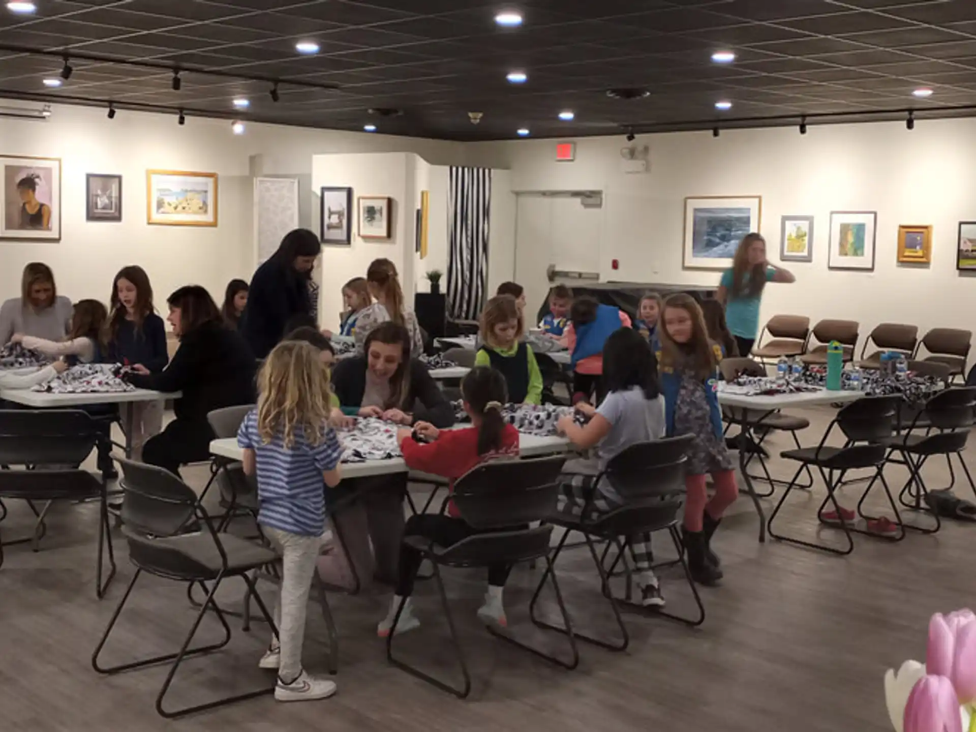 a group of people sitting in a room with tables and chairs